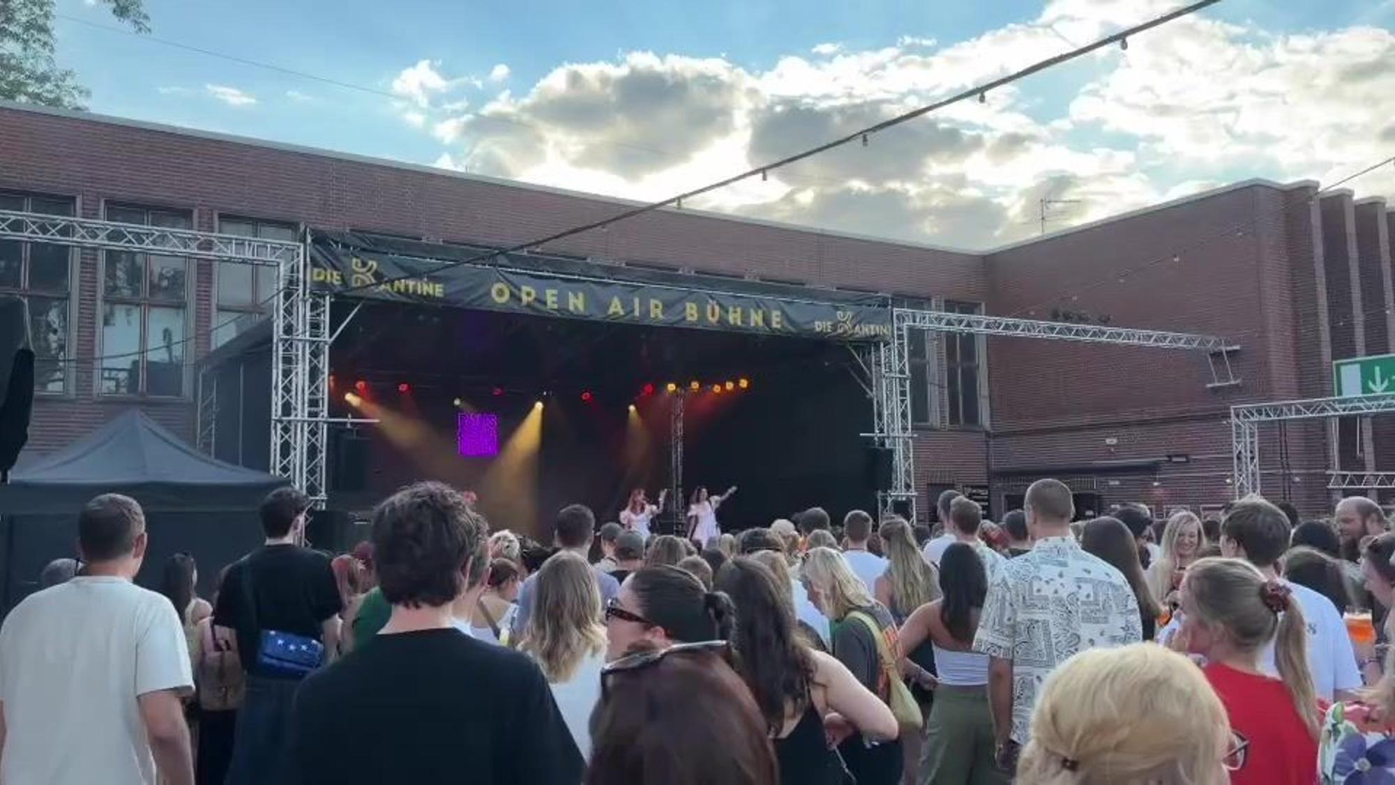 Eine Menschenmenge steht vor einer Open-Air-Bühne.