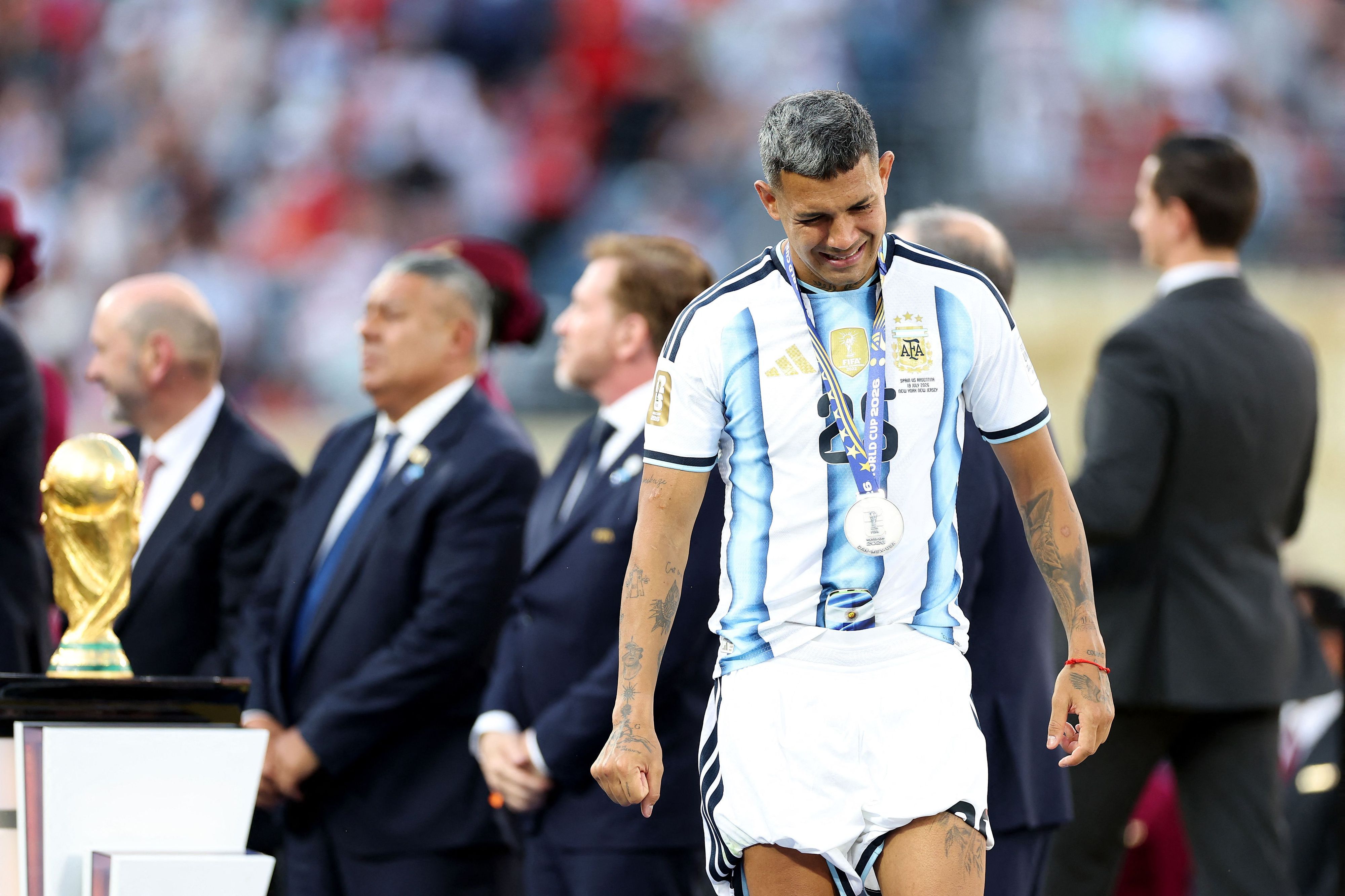 EAST RUTHERFORD, NEW JERSEY - JULY 19: Facundo Medina #25 of Argentina walks past the FIFA World Cup Winner's Trophy at the award ceremony following the FIFA World Cup 2026 Final match between Spain and Argentina at New York New Jersey Stadium on July 19, 2026 in East Rutherford, New Jersey.   Dan Mullan/Getty Images/AFP (Photo by Dan Mullan / GETTY IMAGES NORTH AMERICA / Getty Images via AFP)