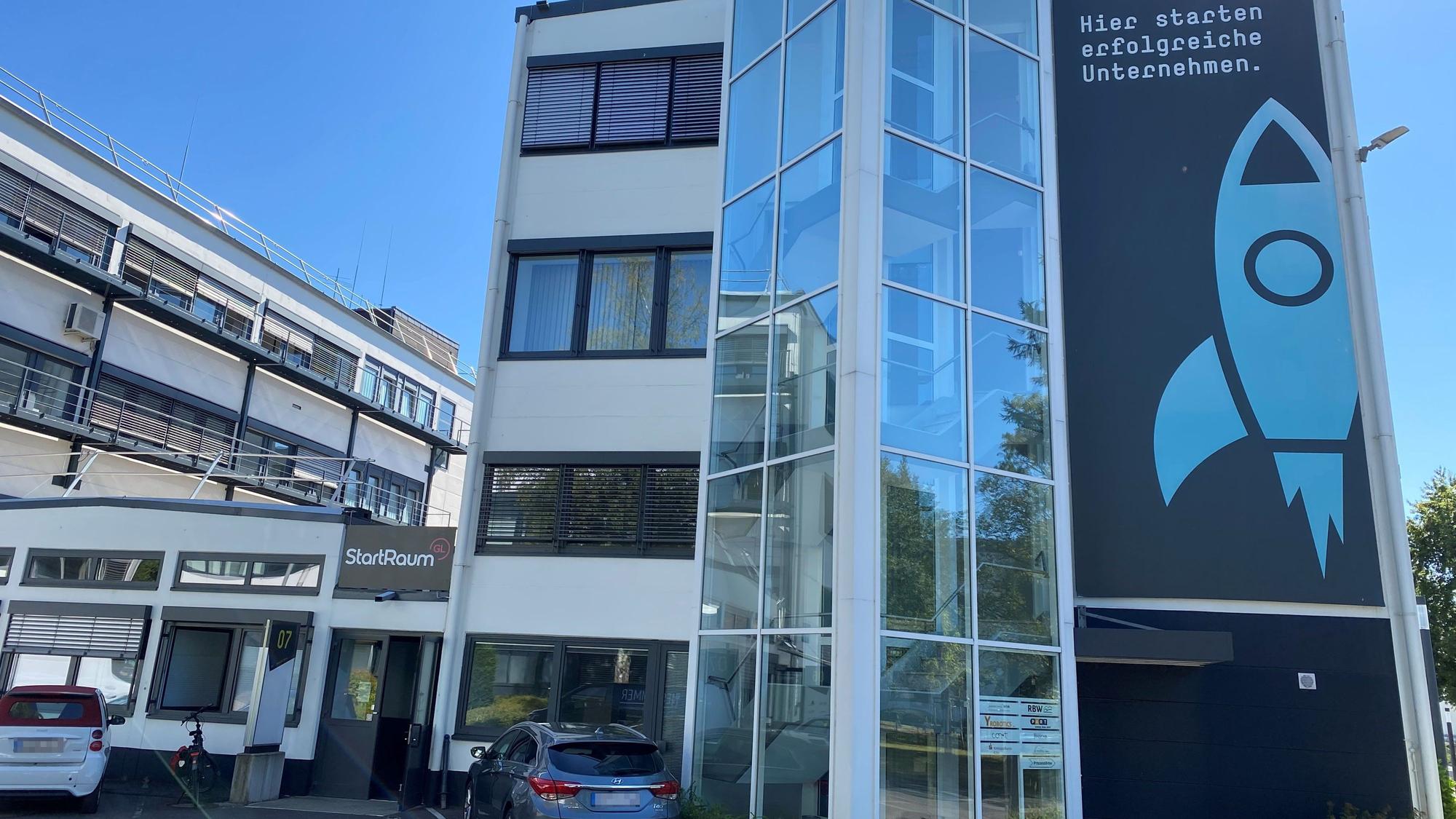 ein dreistöckiges Bürohaus mit einer Raketen-Grafik an der Fassade, daneben ein Flachbau mit dem Schriftzug "Startraum"