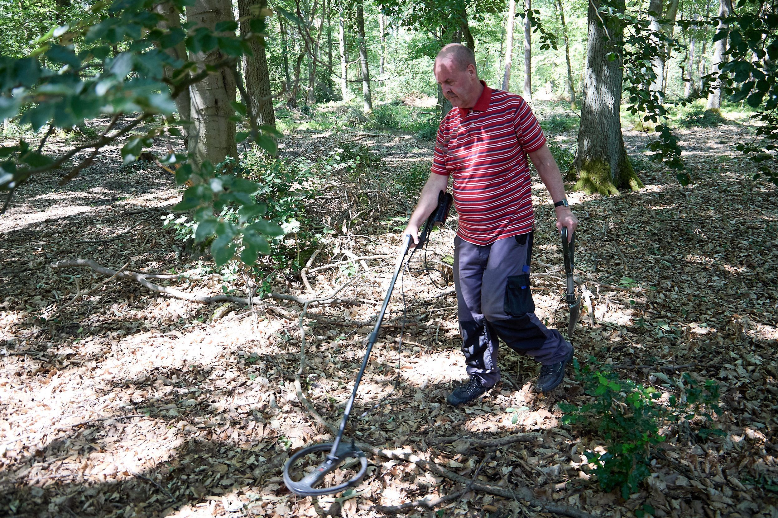 Ein Mann mit einem Metalldetektor im Wald.