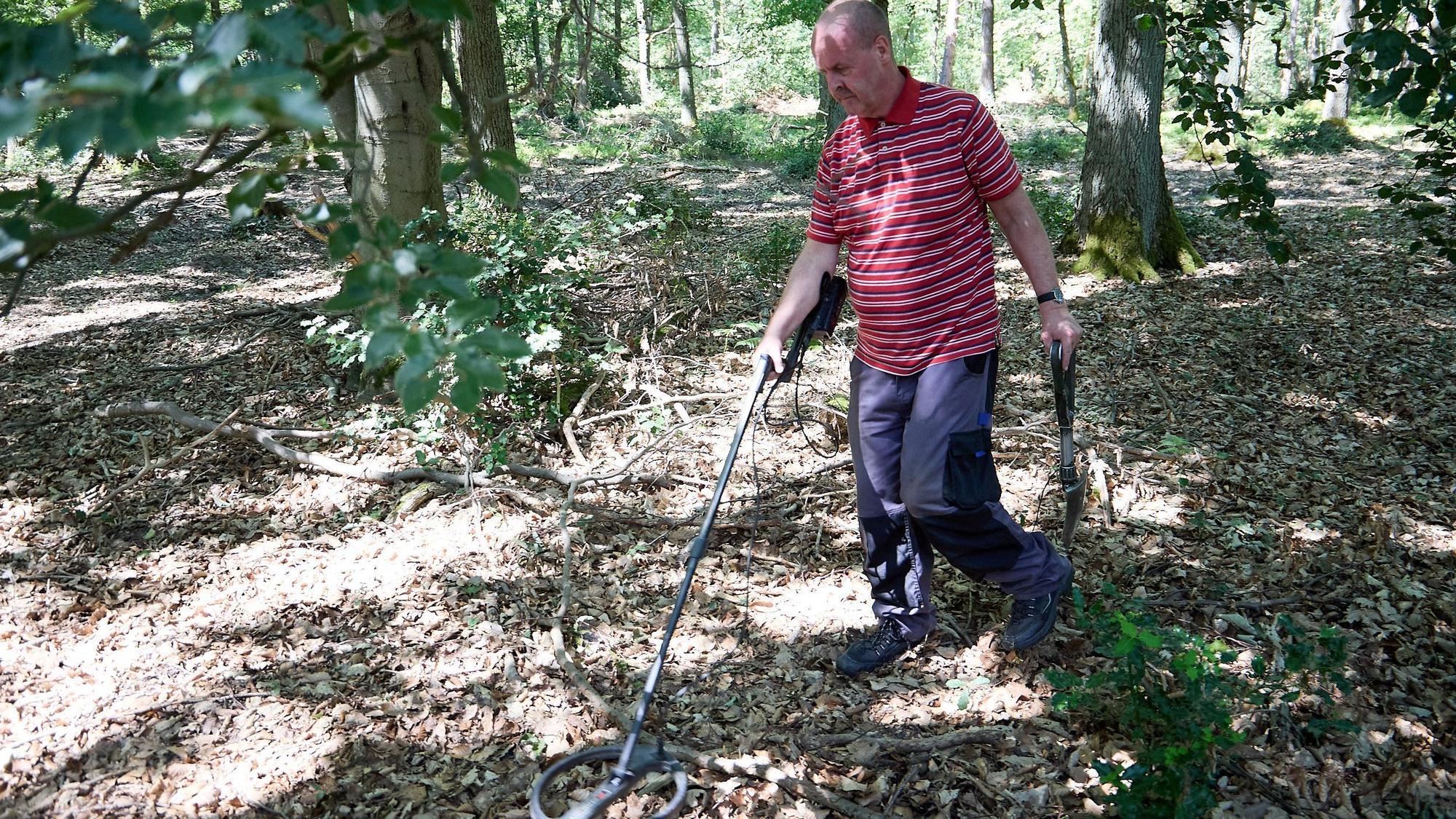 Ein Mann mit einem Metalldetektor im Wald.