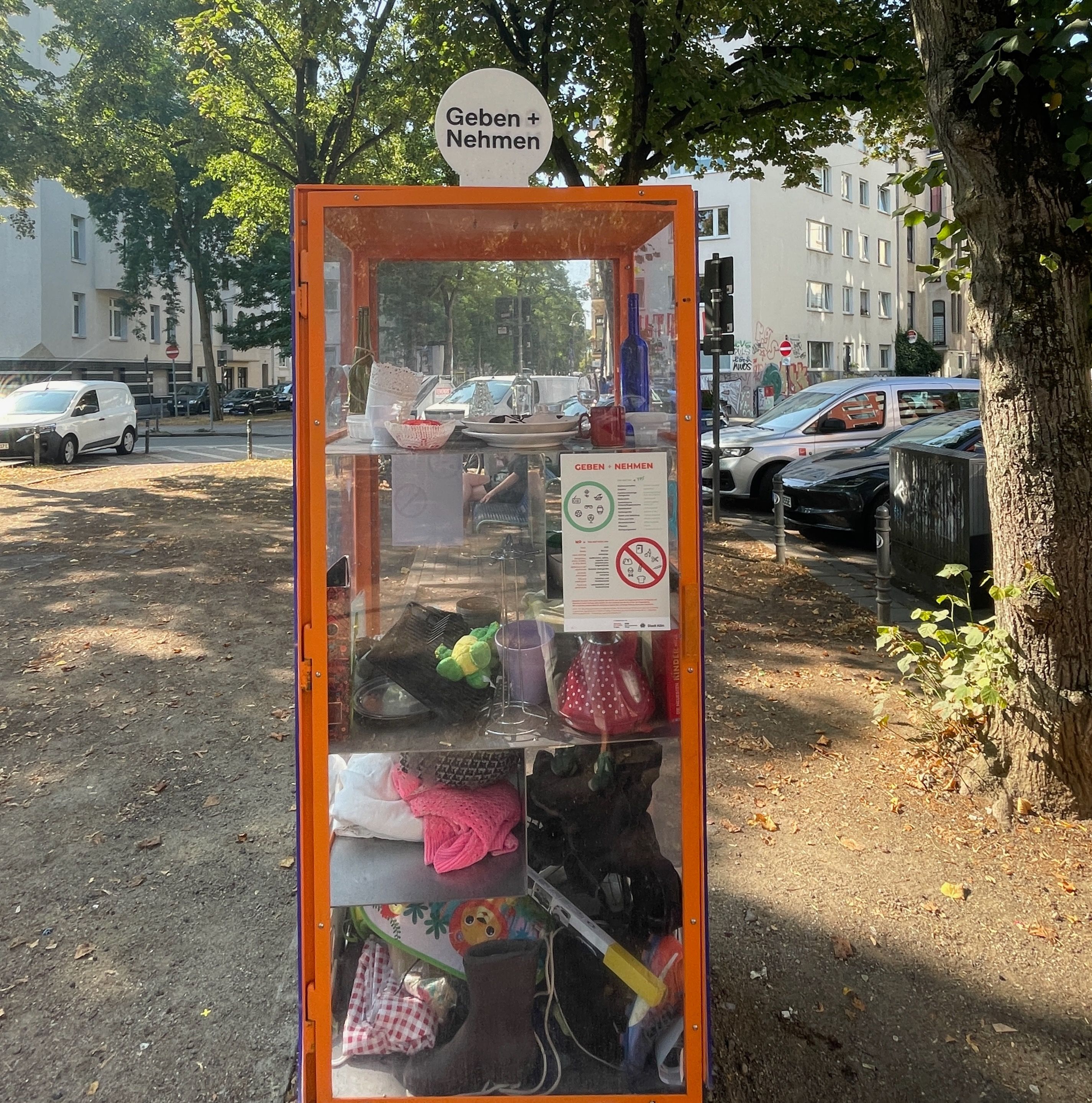 Ein Glasschrank am Eierplätzchen in der Südstadt, in dem es kostenlose Sachen gibt, mit einem Regelzettel.
