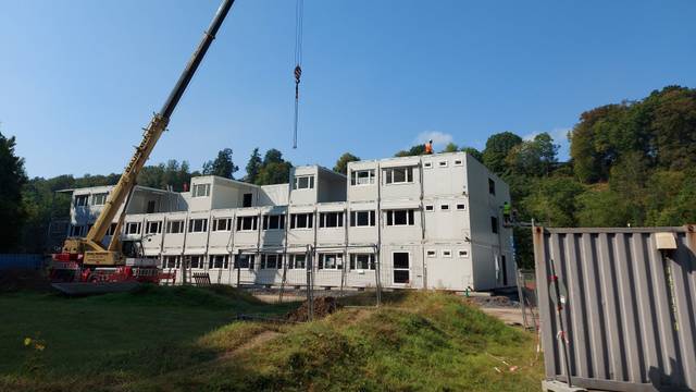 Ein Kran vor einem Containerrohbau.