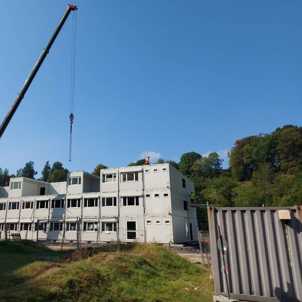 Ein Kran vor einem Containerrohbau.