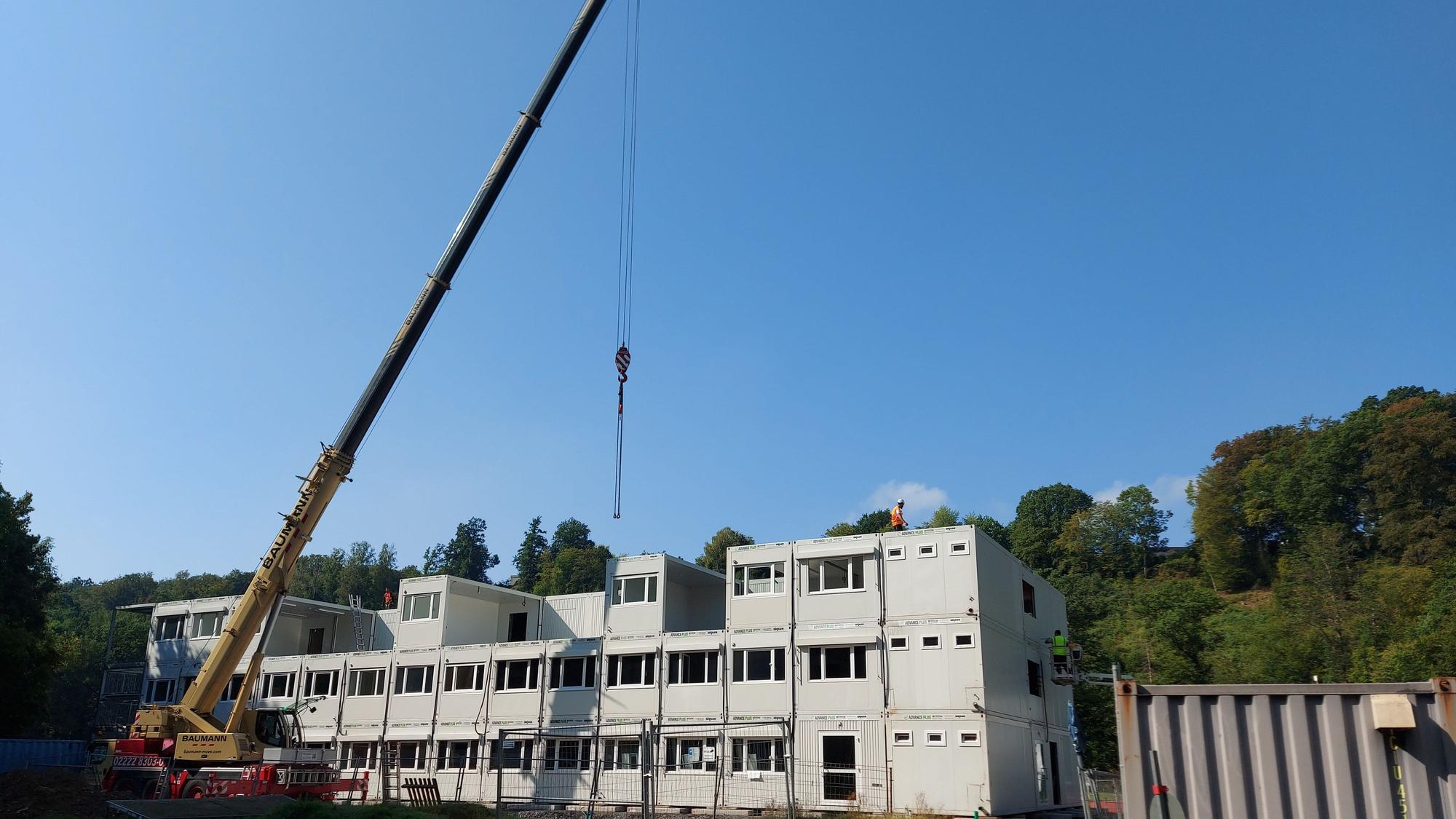 Ein Kran vor einem Containerrohbau.