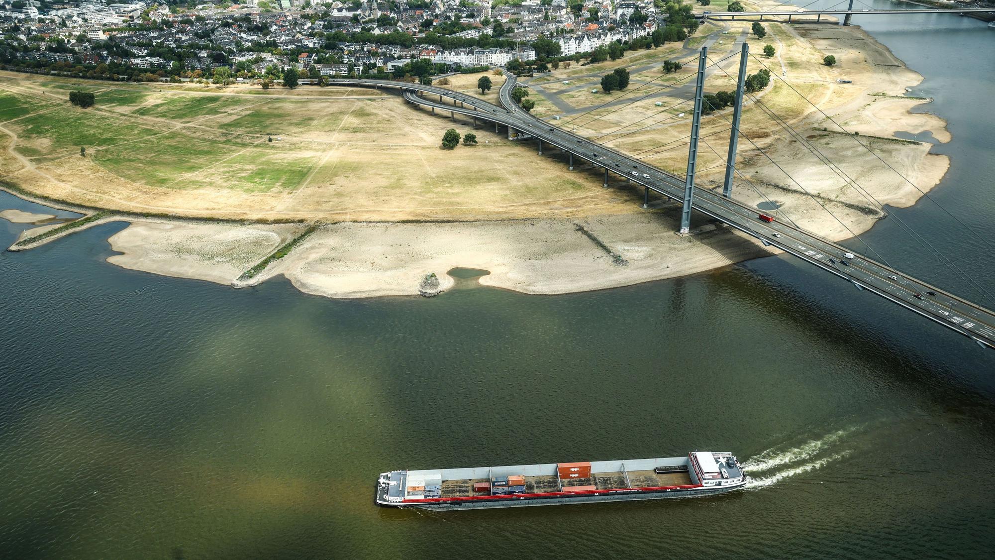 Ein Containerschiff fährt mit geringer Ladung bei Niedrigwasser am Rheinknie in Düsseldorf vorbei.