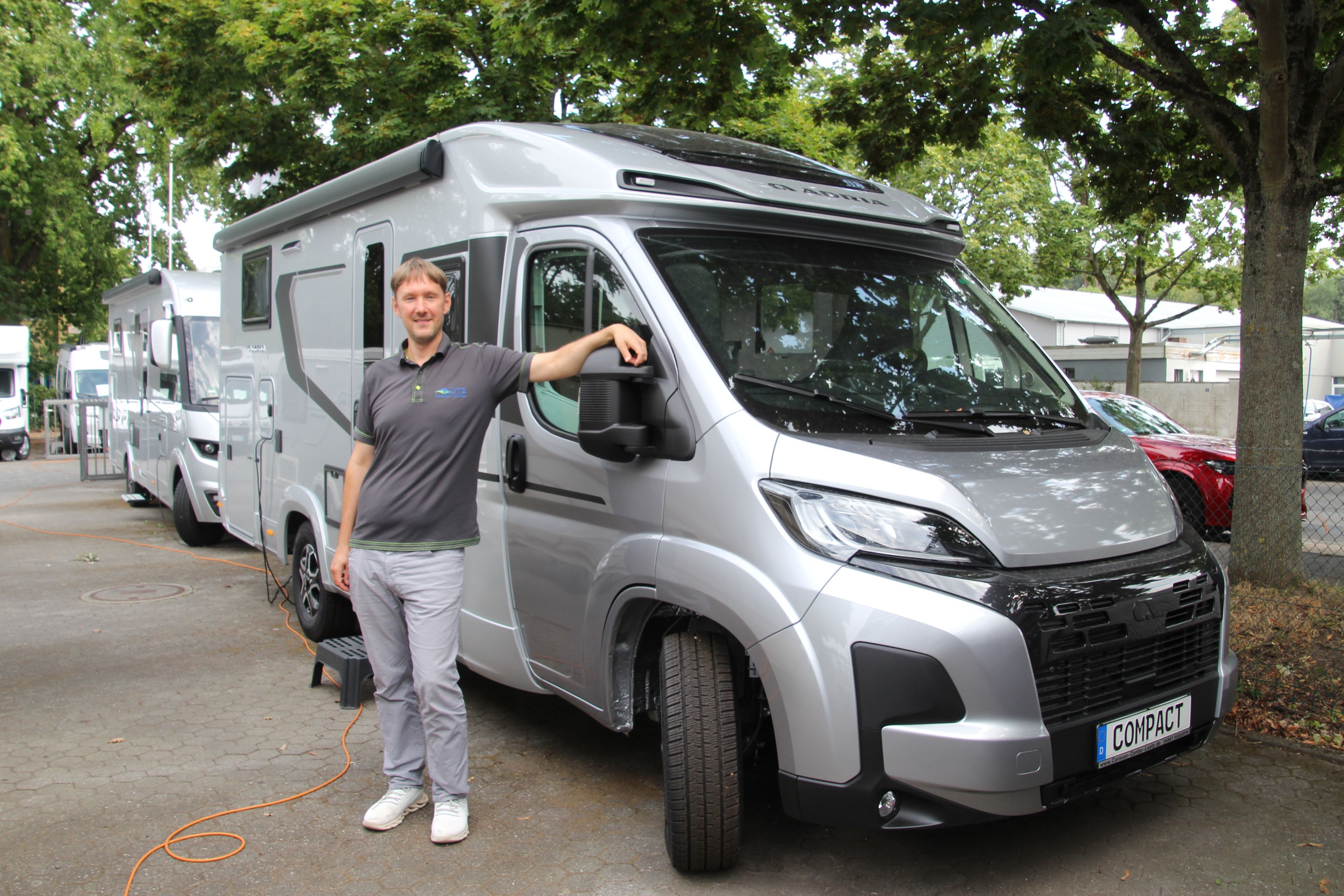Ein Mann steht vor einem silberfarbenen Wohnmobil.