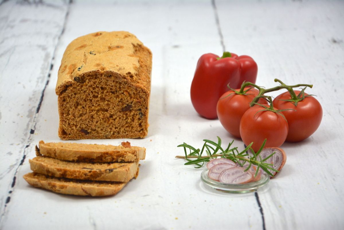 Ein Brot, Tomaten und Rosmarin liegen auf einem Tisch.