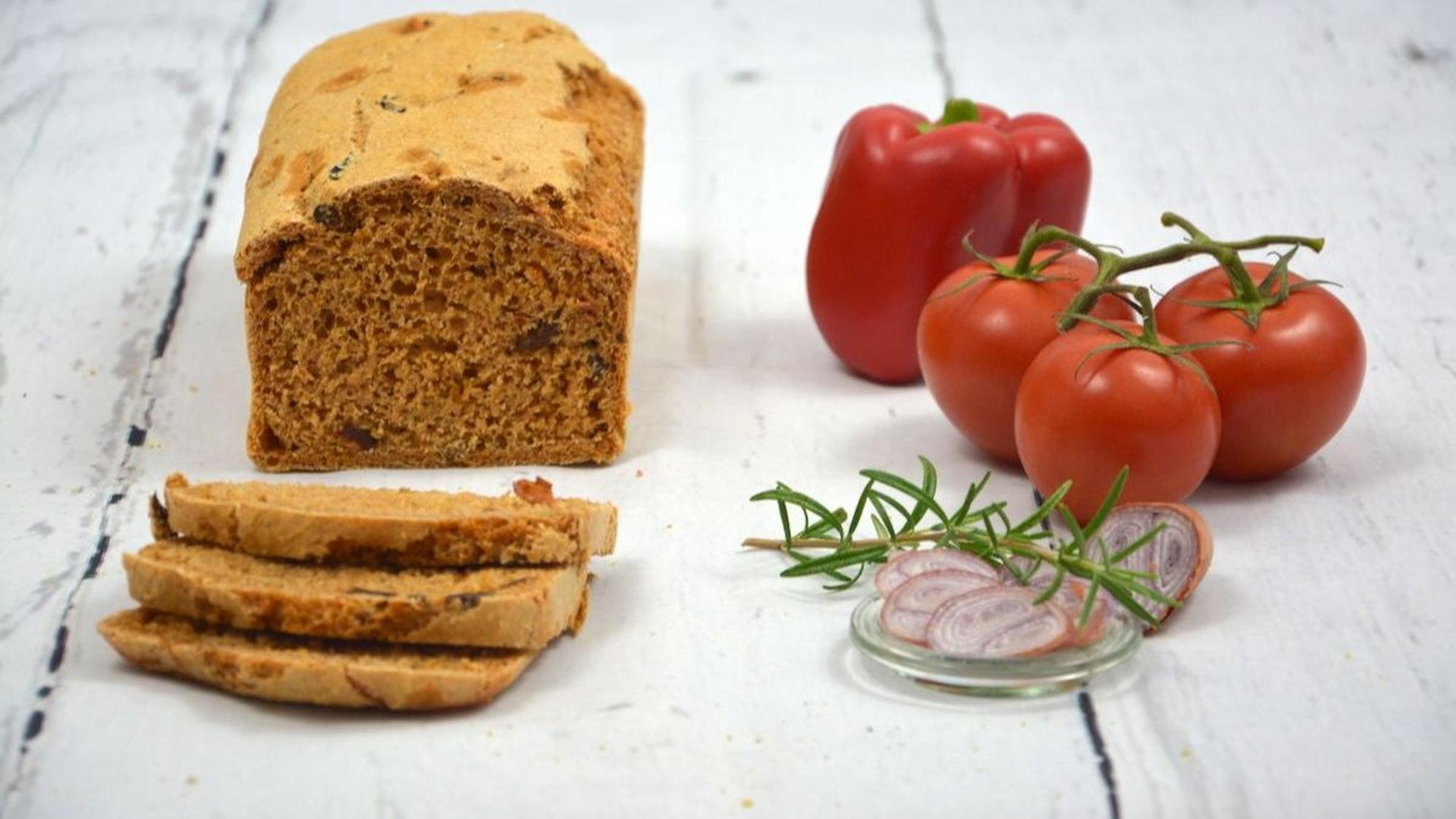 Ein Brot, Tomaten und Rosmarin liegen auf einem Tisch.