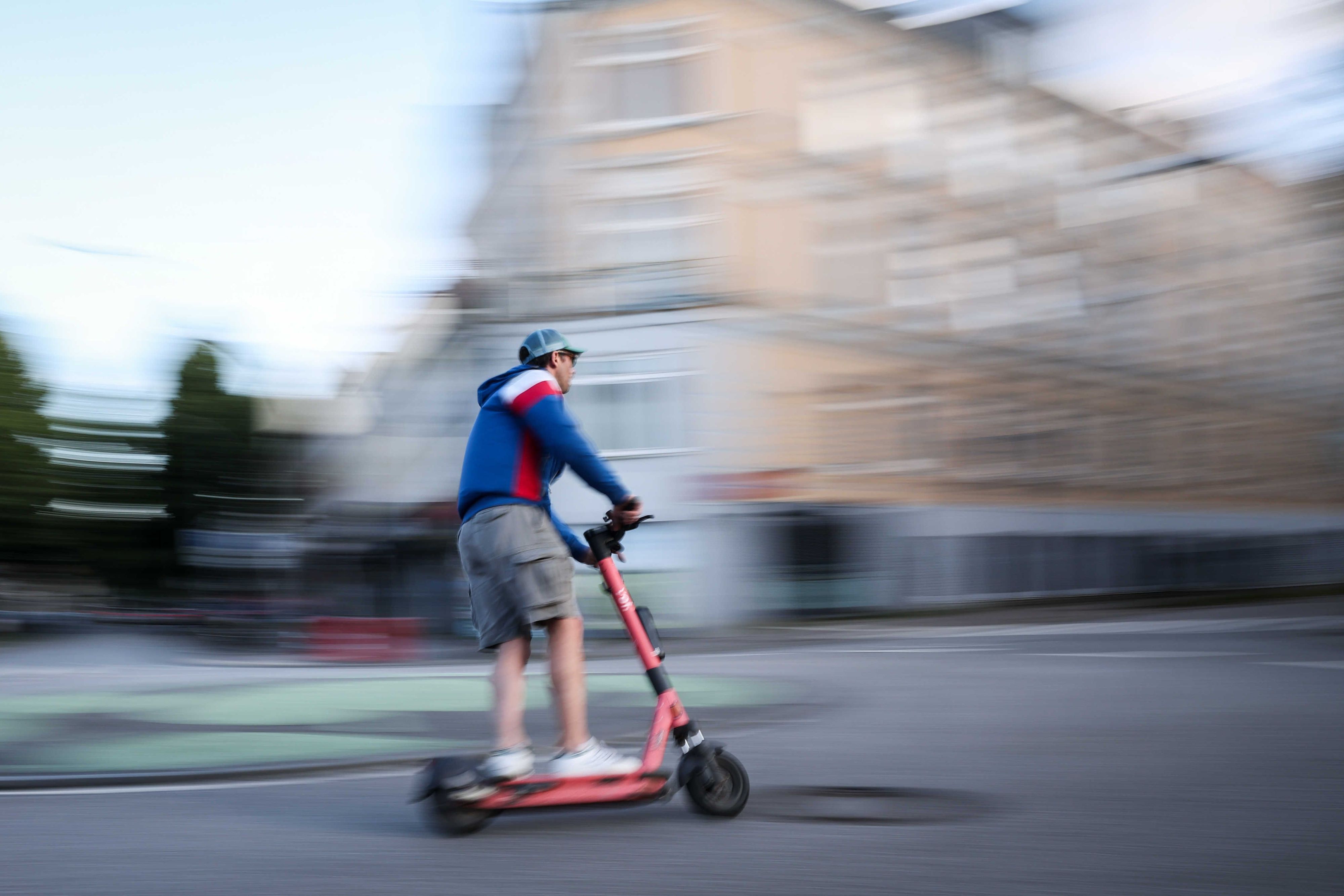 Ein Mann ist auf einem E-Scooter unterwegs (Aufnahme mit langer Verschlusszeit).