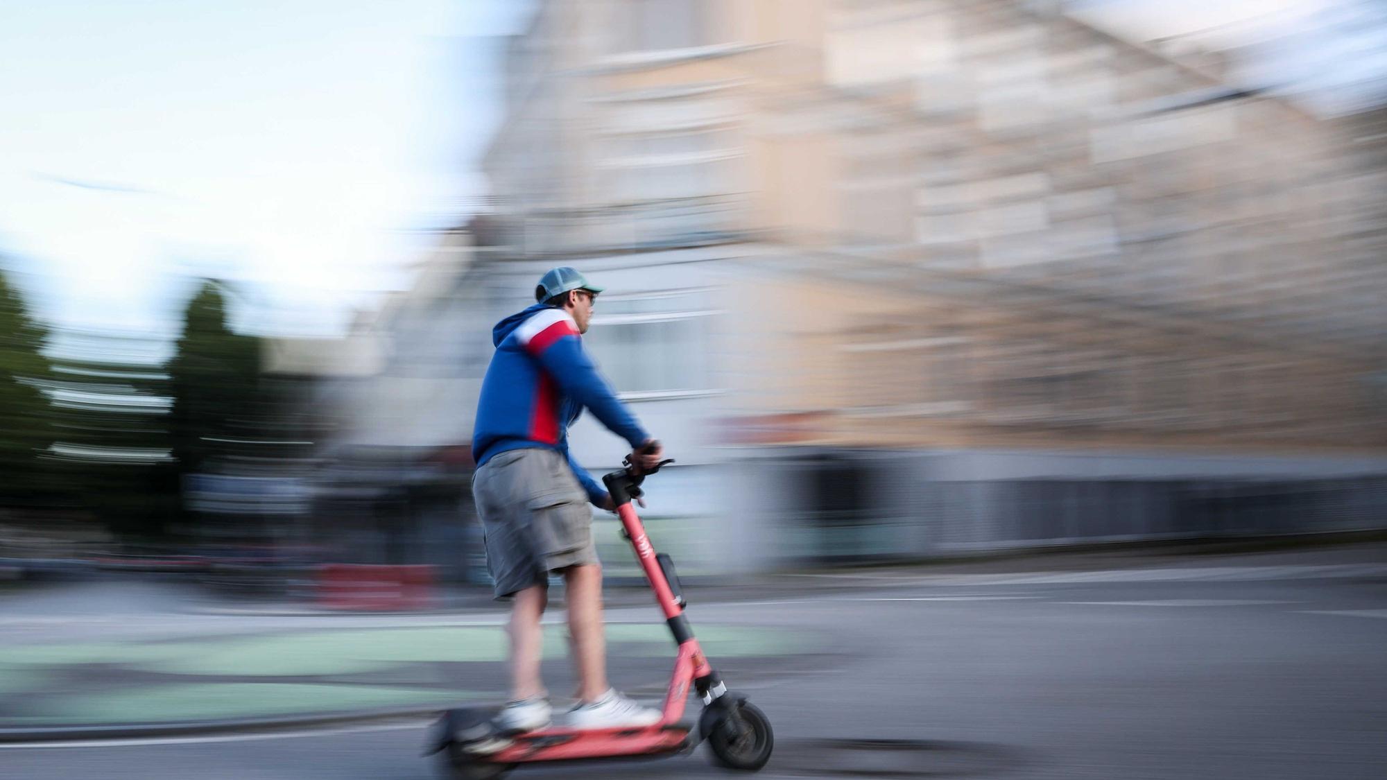Ein Mann ist auf einem E-Scooter unterwegs (Aufnahme mit langer Verschlusszeit).