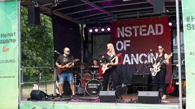 Ein Gitarrist, die Sängerin, die ebenfalls Gitarre spielt, und eine Bassistin stehen vorne auf der Bühne, im Hintergrund ist die Schlagzeugerin zu sehen.