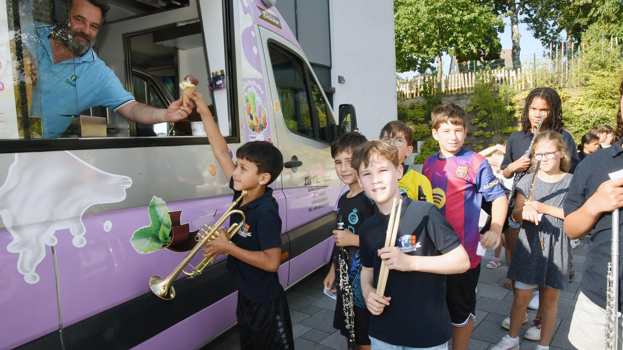 Kinder mit Musikinstrumenten stehen vor einem Eiswagen.