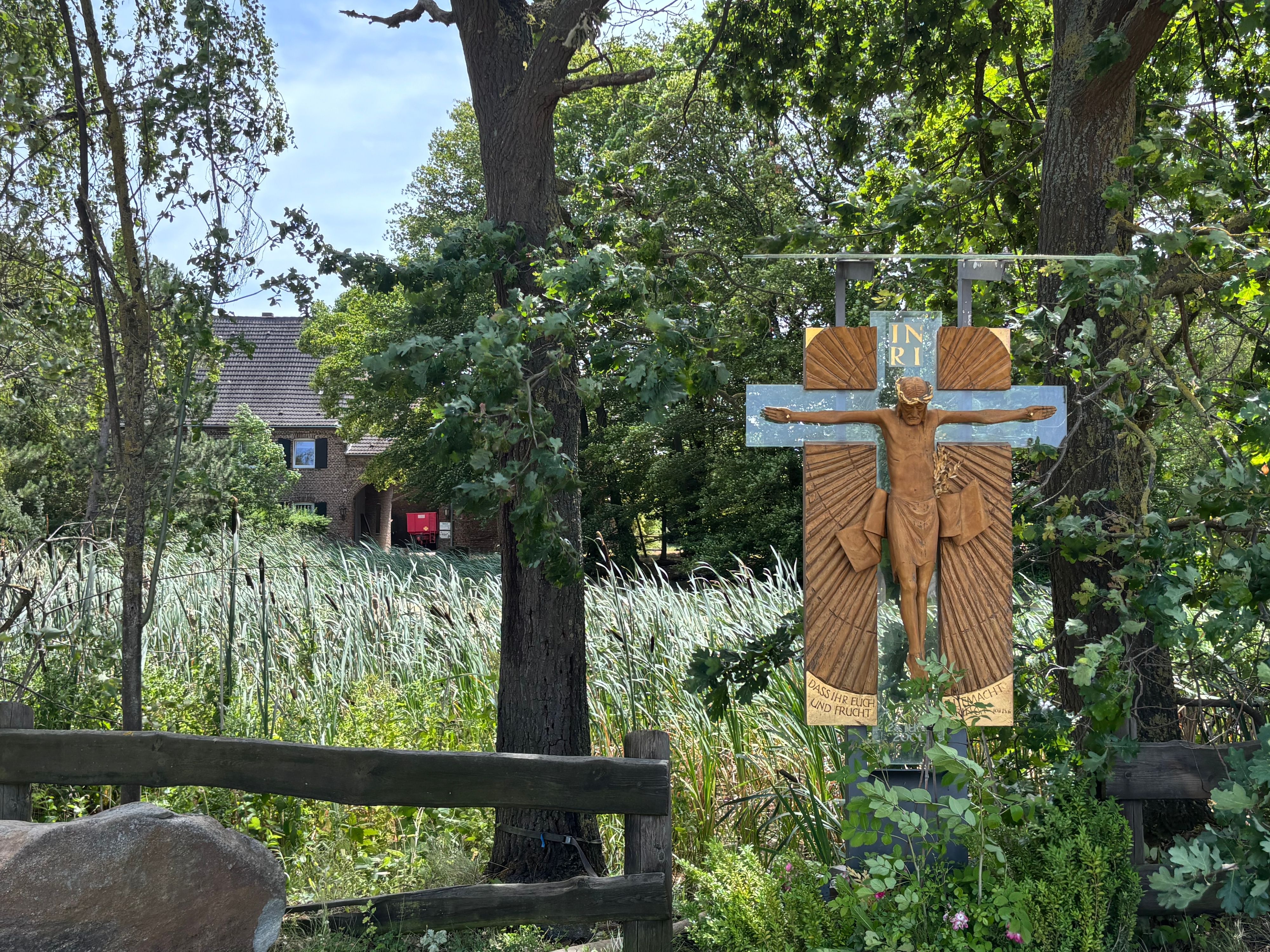 Das Foto zeigt ein Kreuz vor einem Gutshof.