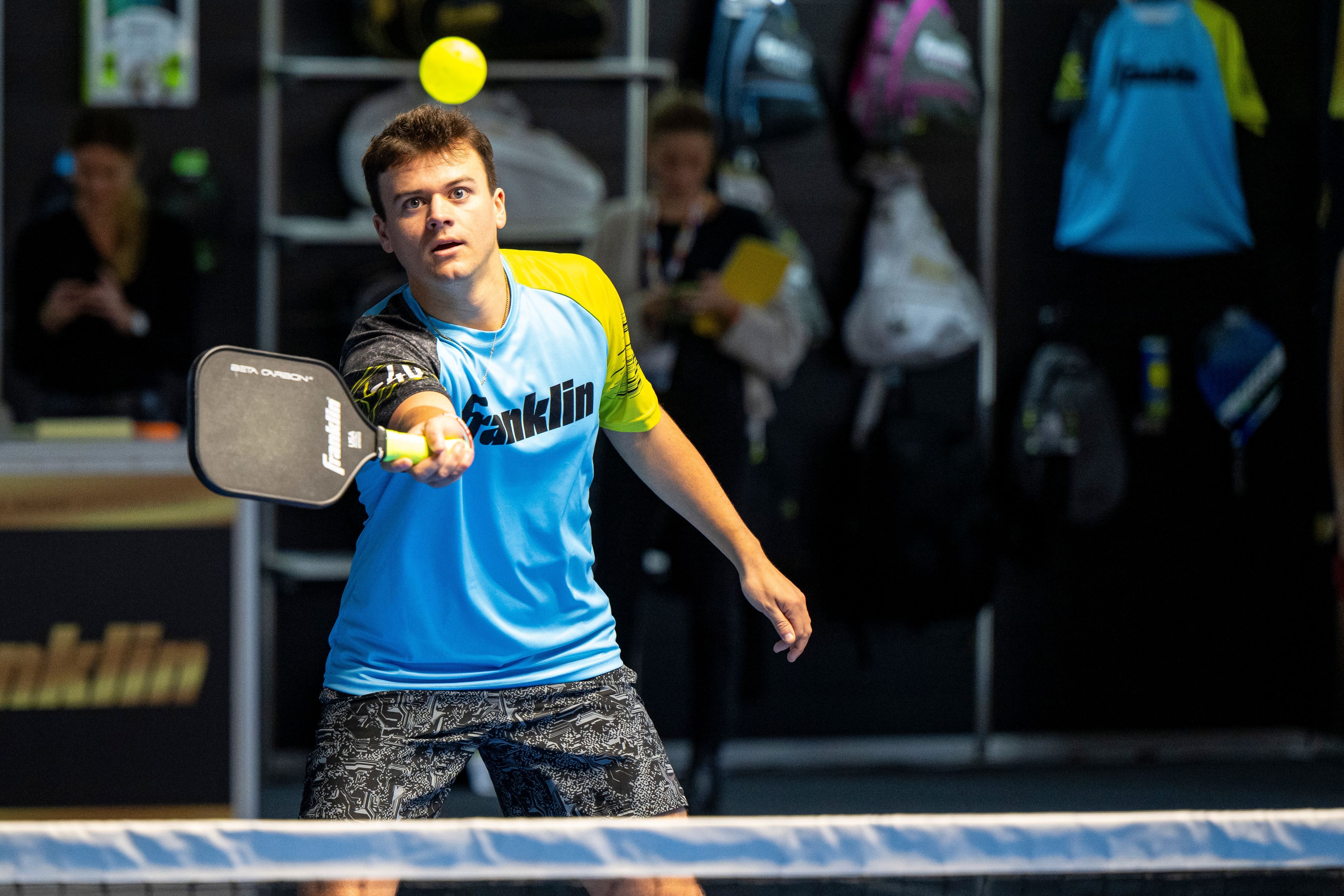 Ein junger Mann schlägt mit einem Pickleball-Schläger nach einem gelben Ball.