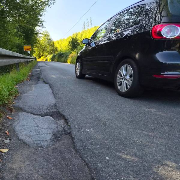 Ein Auto neben kaputtem Asphalt.