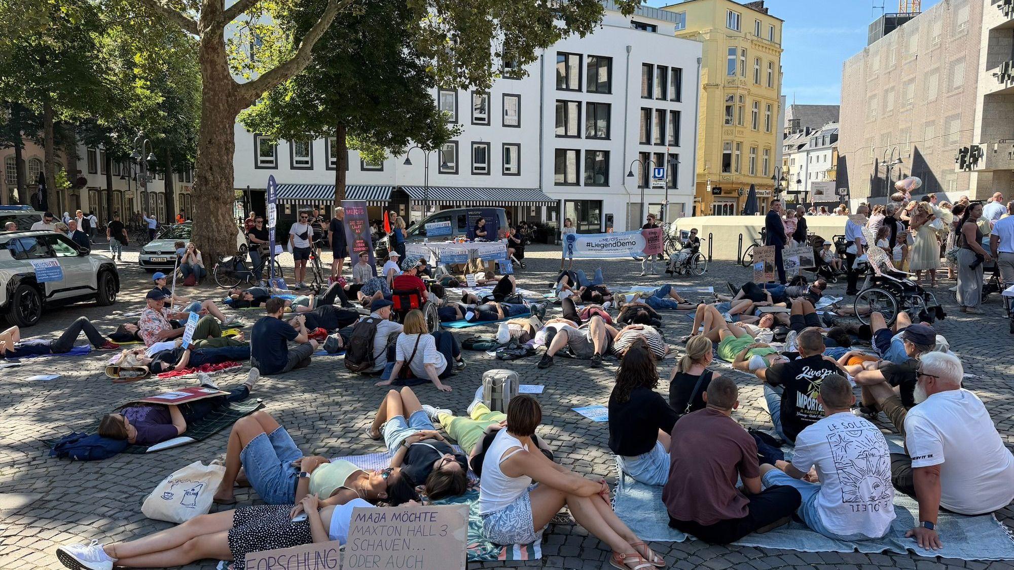 Bei der Liegend-Demo haben Menschen in Köln auf die Krankheit ME/CFS aufmerksam gemacht. Oft verbringen die Betroffenen den Tag im Bett – in abgedunkelten Räumen.