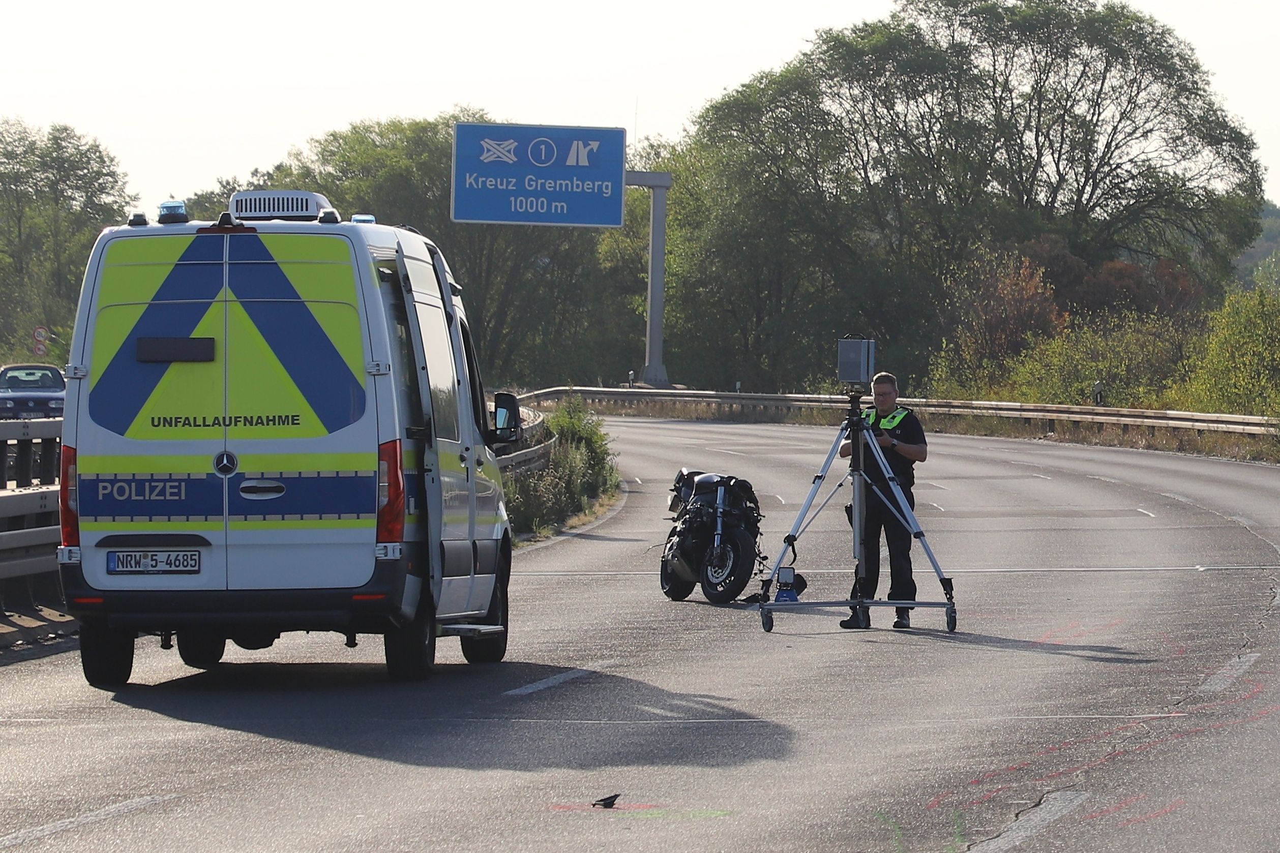 Ein Polizist nimmt Spuren mit einem Scanner auf. Bei einem Zusammenstoß zweier Motorräder auf der L124 in Köln sind zwei Männer ums Leben gekommen.