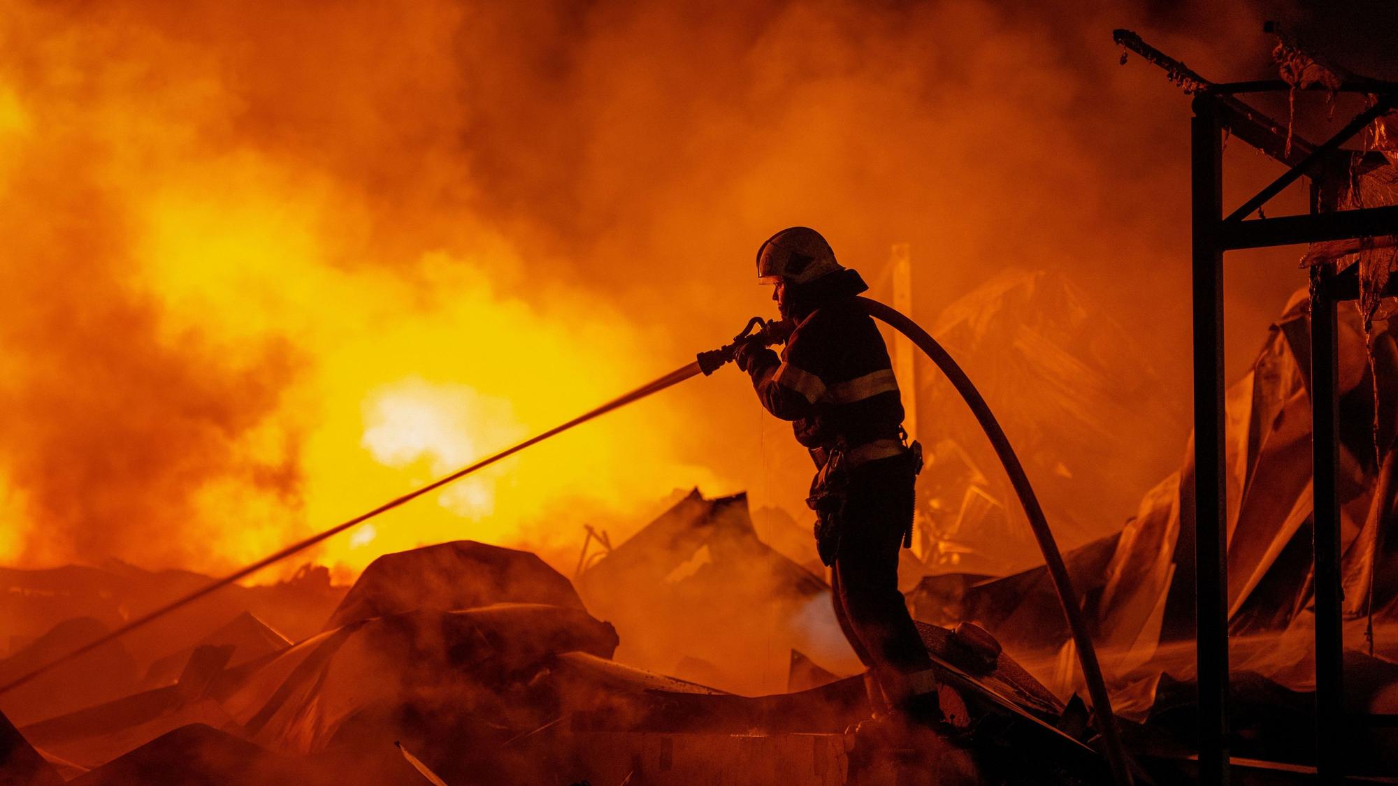 Feuerwehrleute löschten einen Brand, nachdem russische Raketen ein Lagerhaus getroffen hatten.