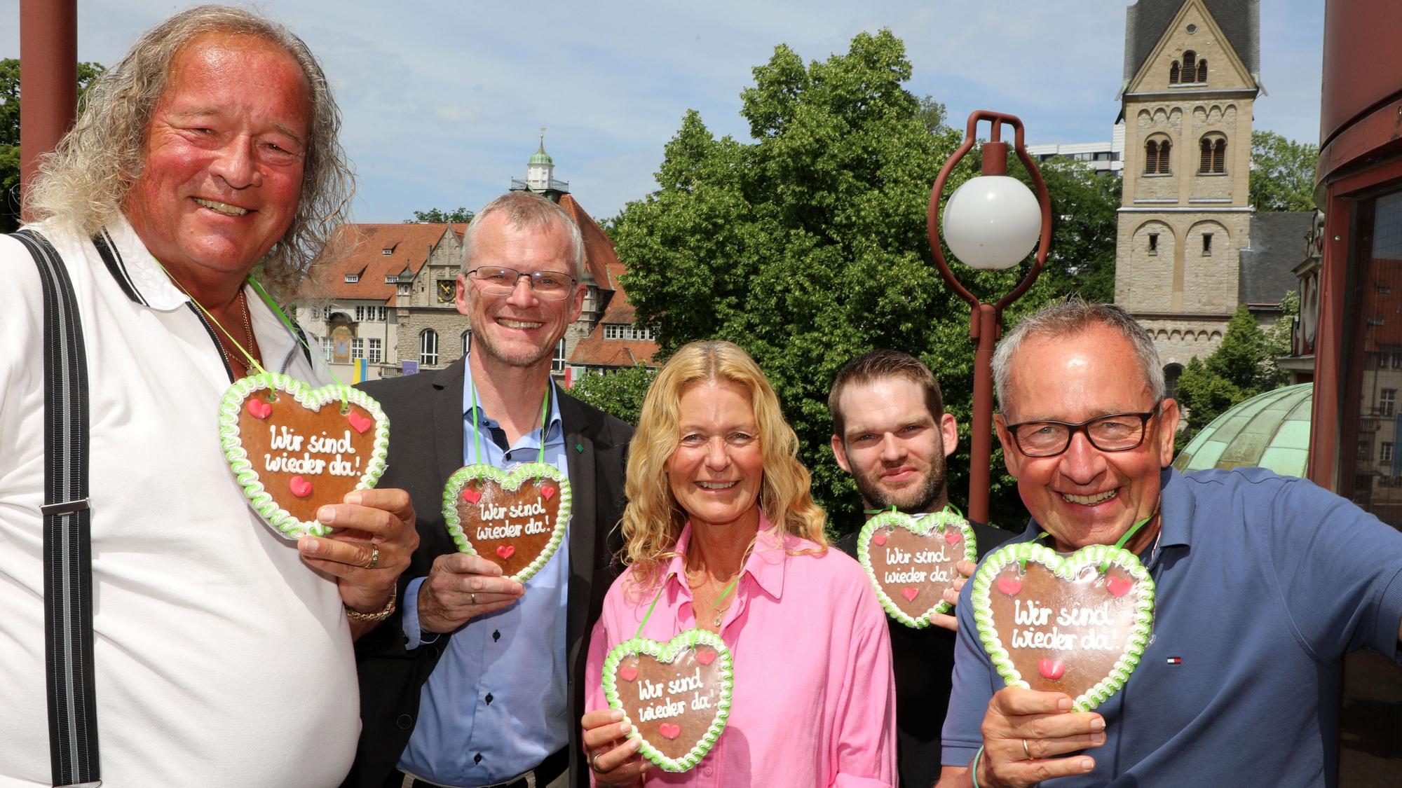 Burkhardt Unrau, Frank Stein, Ute Unrau, Marco Euler und Ferdinand Linzenich stehen mit Lebkuchenherzen mit der Aufschrift „Wir sind wieder da“ auf der Treppe des Bergischen Löwens. Im Hintergrund ist der Konrad-Adenauer-Platz mit Rathaus und Kirche zu sehen.