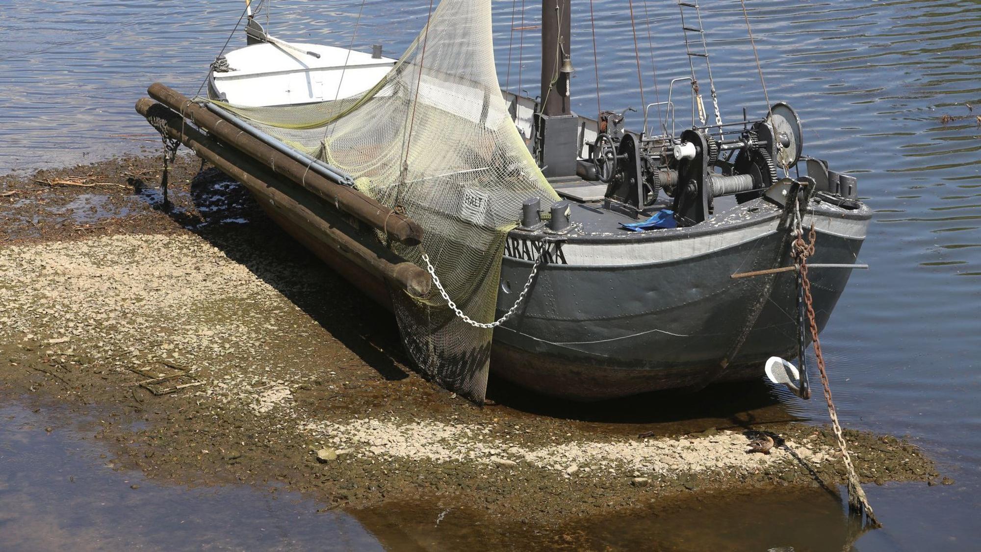 Ein historisches Schiff mit einem flachen Boden liegt auf Grund.