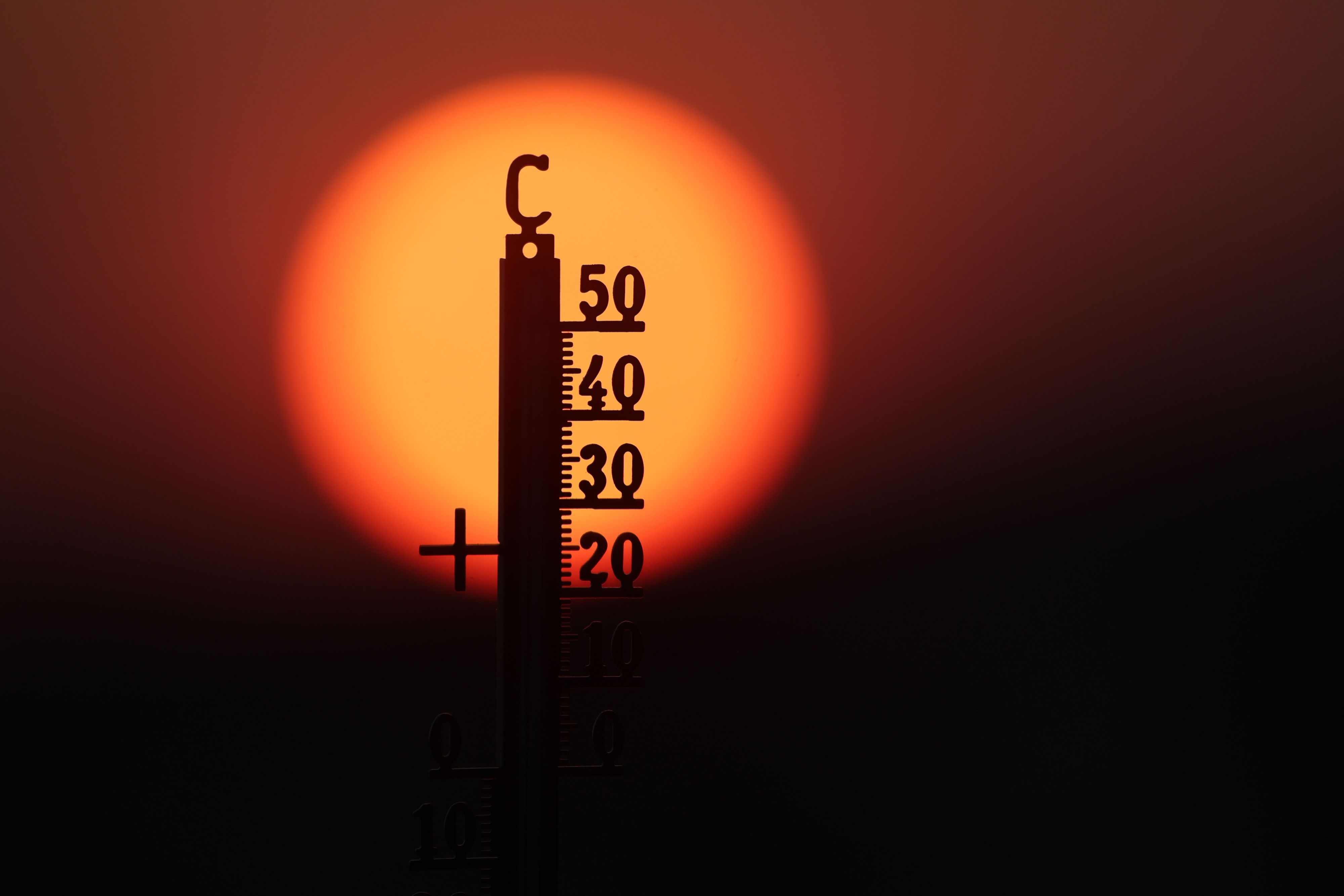 Hinter einem Thermometer geht am Morgen die Sonne auf.