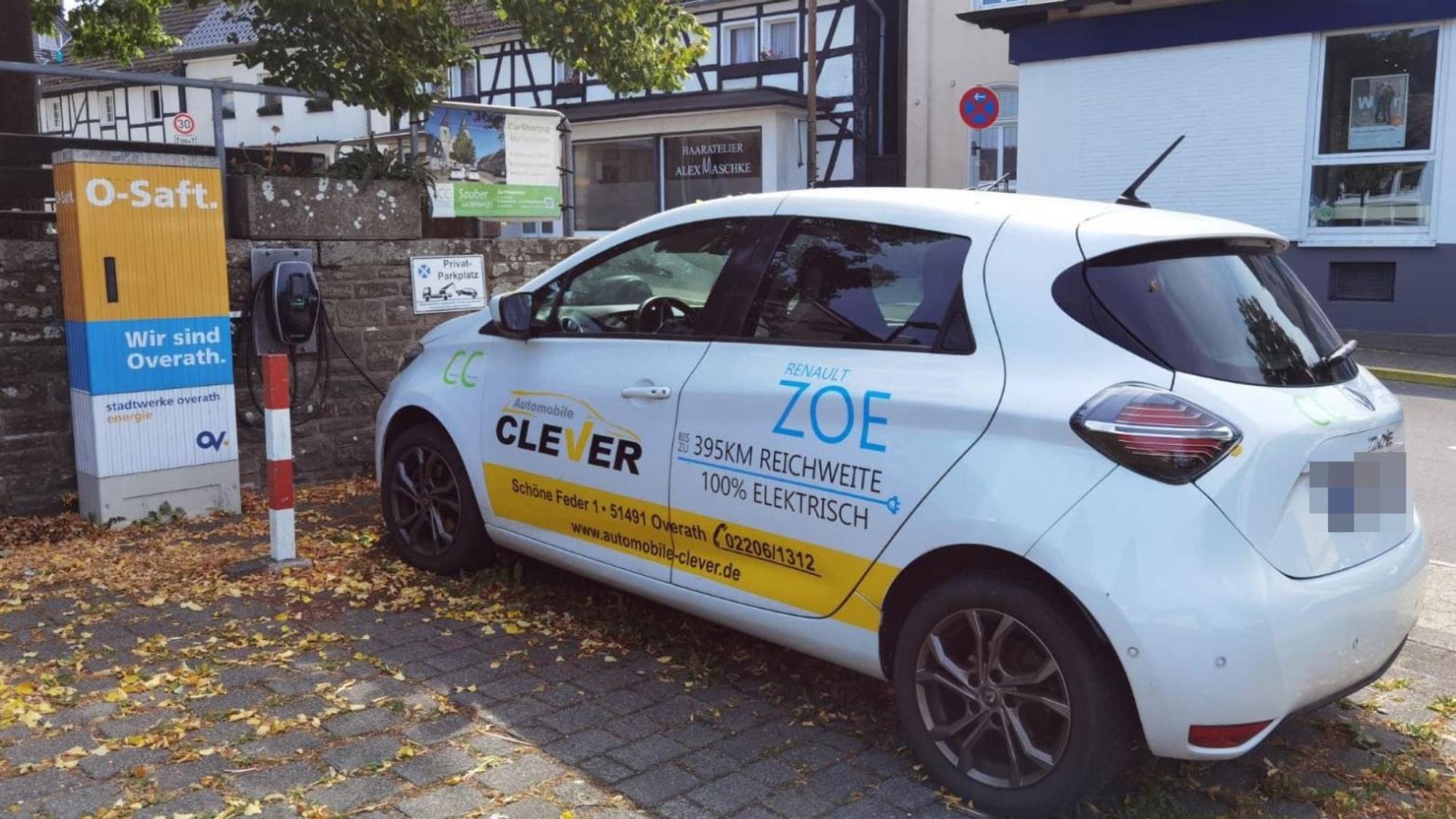 Ein E-Auto steht an einer Ladestation auf einem Parkplatz.