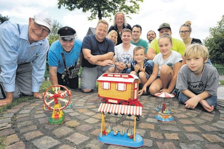 Schausteller und Vertreter der Humanitären Hilfe Overath knien und hocken auf dem privaten „Konrad-Adenauer-Platz“ mit Kirmes von Ute und Burkhardt Unrau in Bergisch Gladbach-Hebborn.