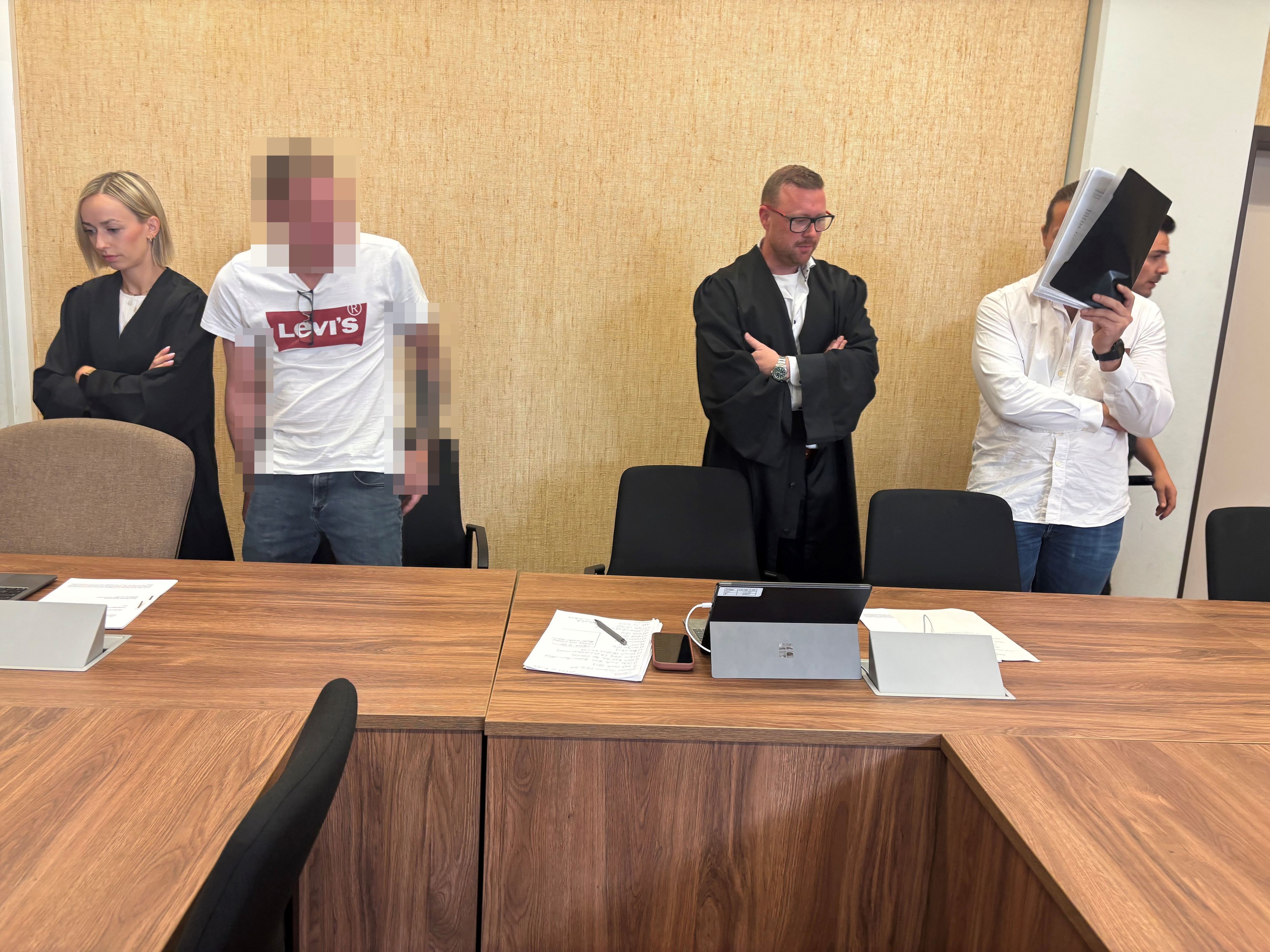 Zwei Männer stehen mit ihren Anwälten vor Gericht.
