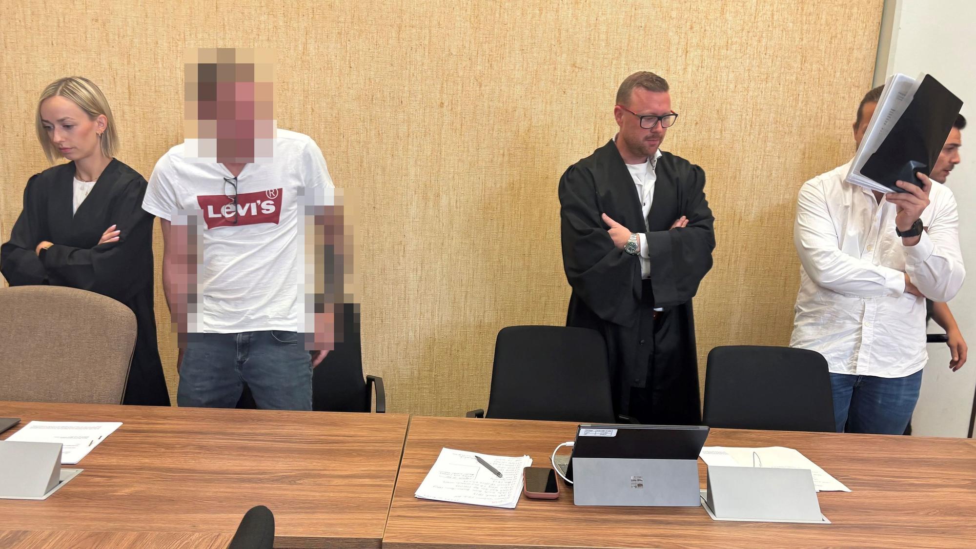 Zwei Männer stehen mit ihren Anwälten vor Gericht.