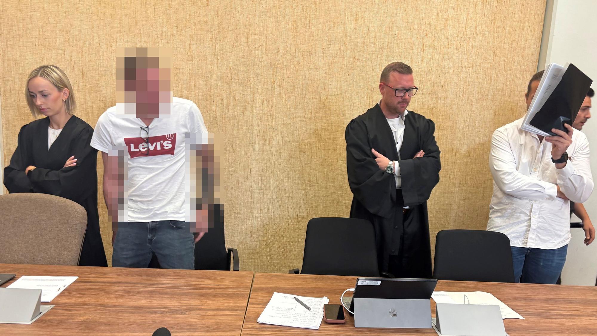 Zwei Männer stehen mit ihren Anwälten vor Gericht.