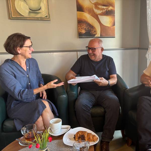 Das Foto zeigt eine Frau und zwei Männer in drei Sesseln, die sich unterhalten.