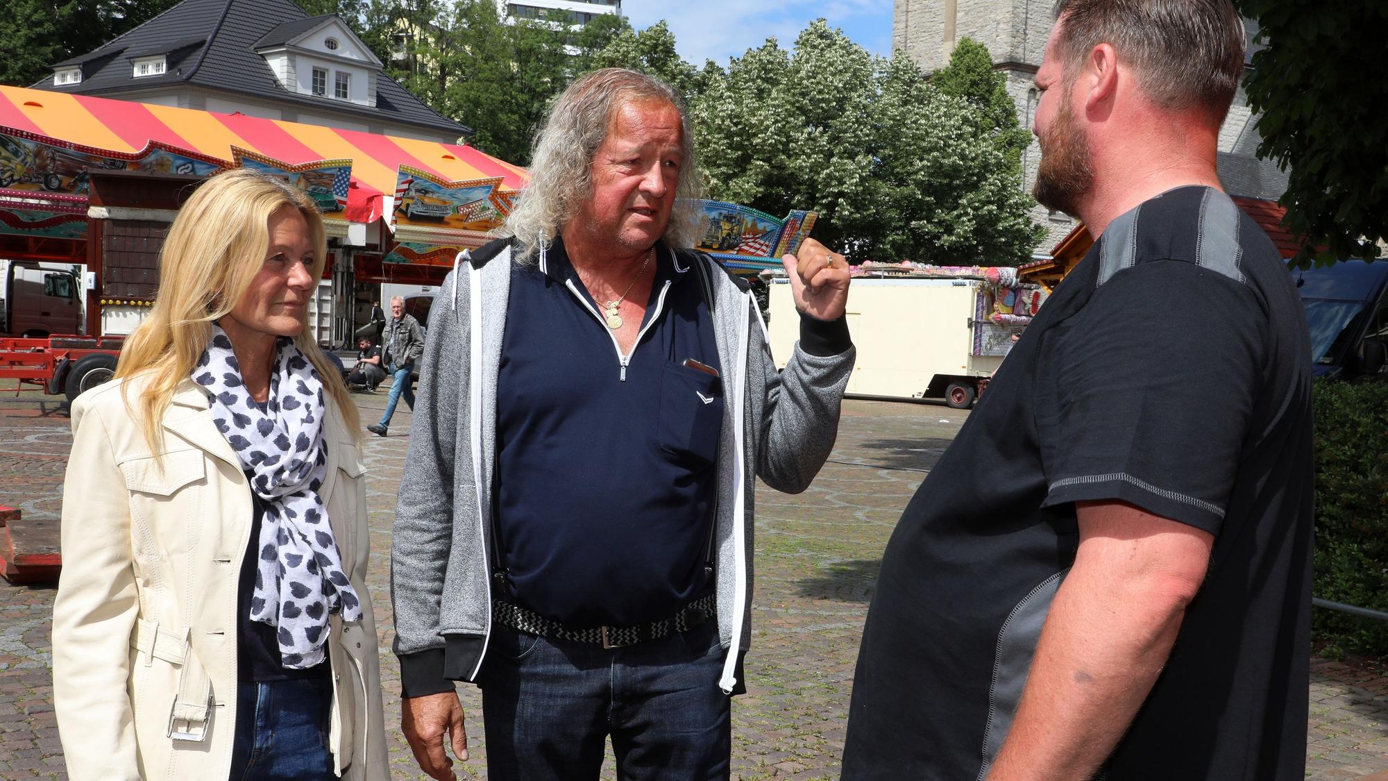 Ute Unrau und Burkhardt Unrau stehen mit einem Schausteller auf dem Bergisch Gladbacher Kirmesplatz.