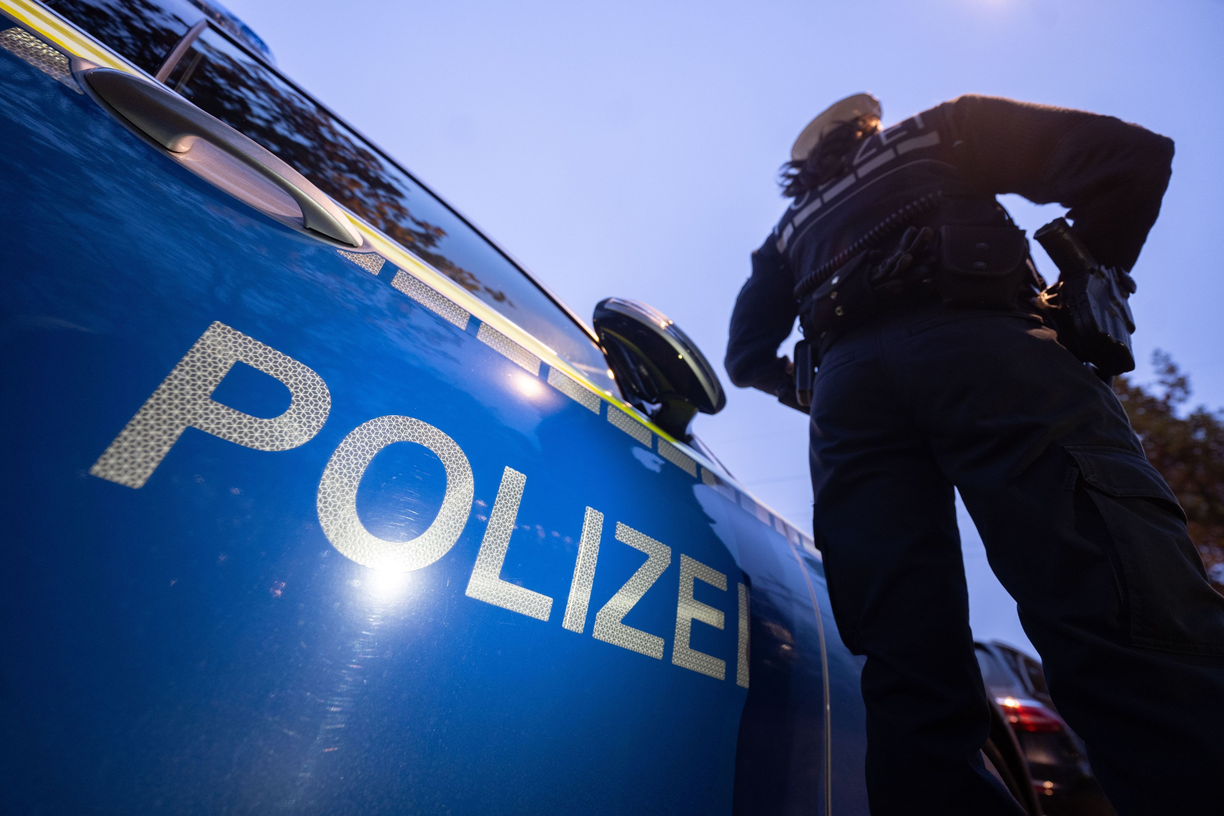 Eine Polizistin steht neben einem Polizeifahrzeug.