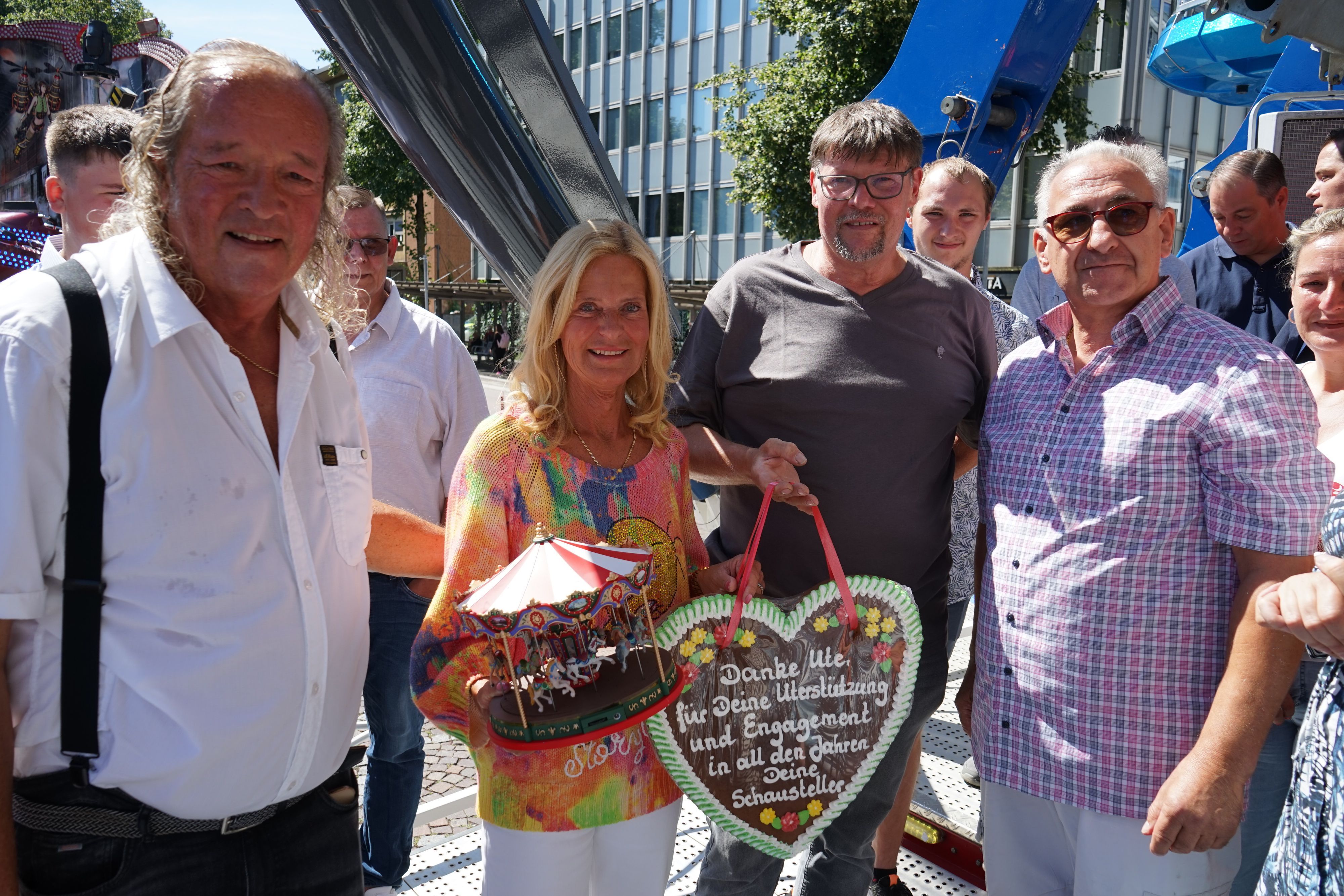 Ute Unrau steht mit ihrem Mann Burkhardt und Schaustellern auf einem Kirmesgeschäft der Laurentiuskirmes 2026 und wird verabschiedet.