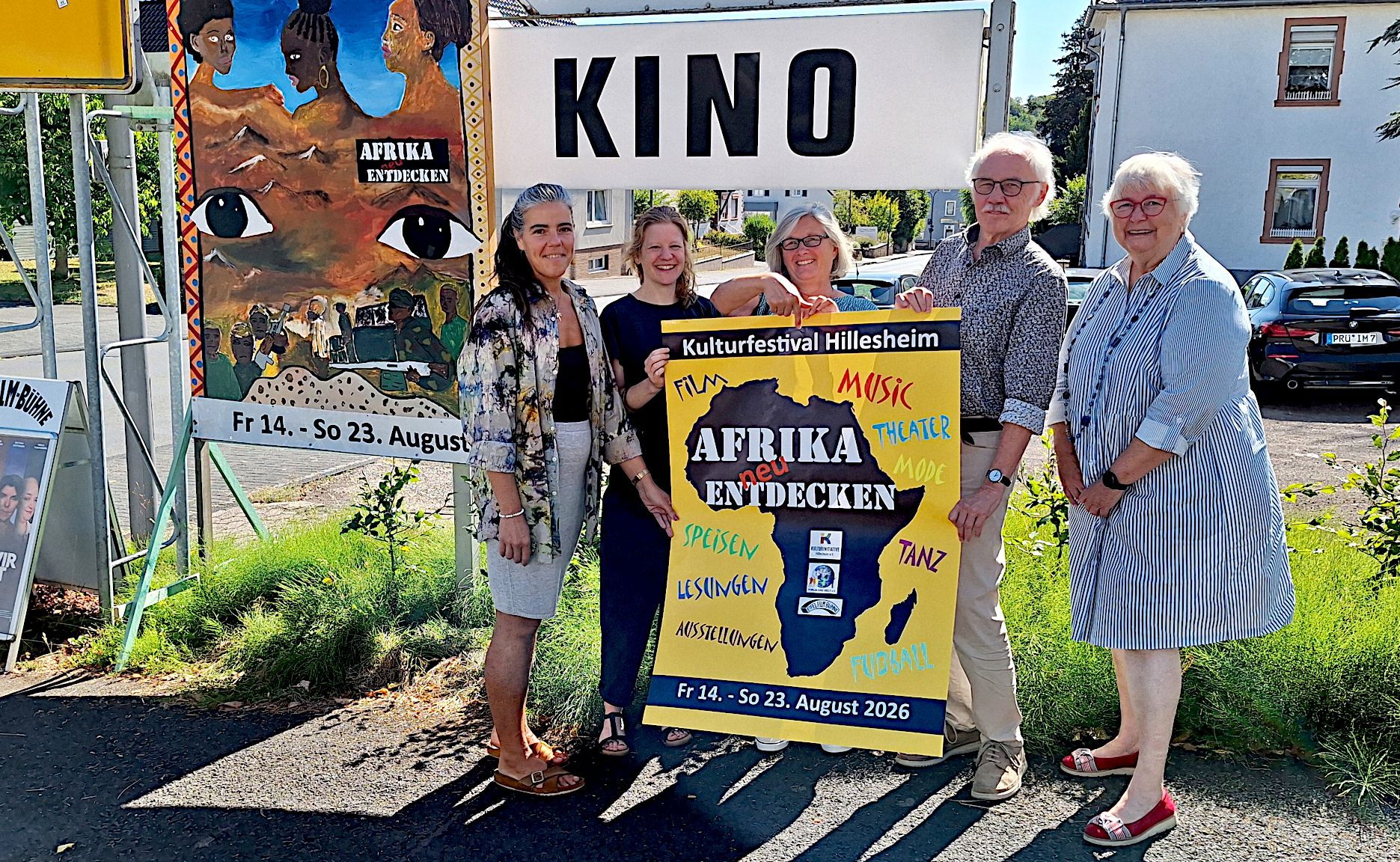 Vier Frauen und ein Mann halten das Plakat in den Händen, das auf das Festival „Afrika neu entdecken“ in Hillesheim hinweist.