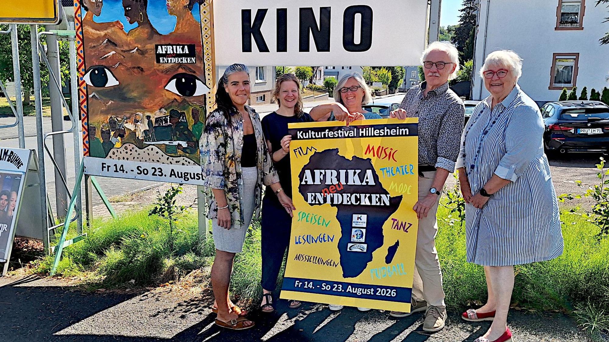 Vier Frauen und ein Mann halten das Plakat in den Händen, das auf das Festival „Afrika neu entdecken“ in Hillesheim hinweist.