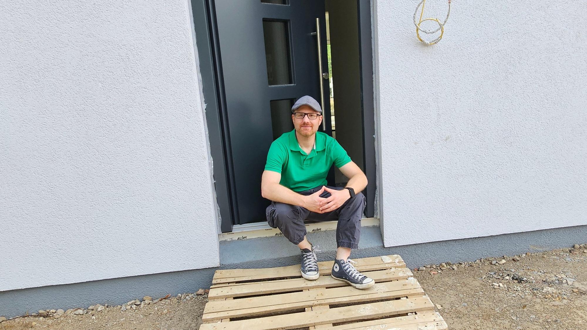 Das Bild zeigt Lars Ollig sitzend vor seinem Haus.