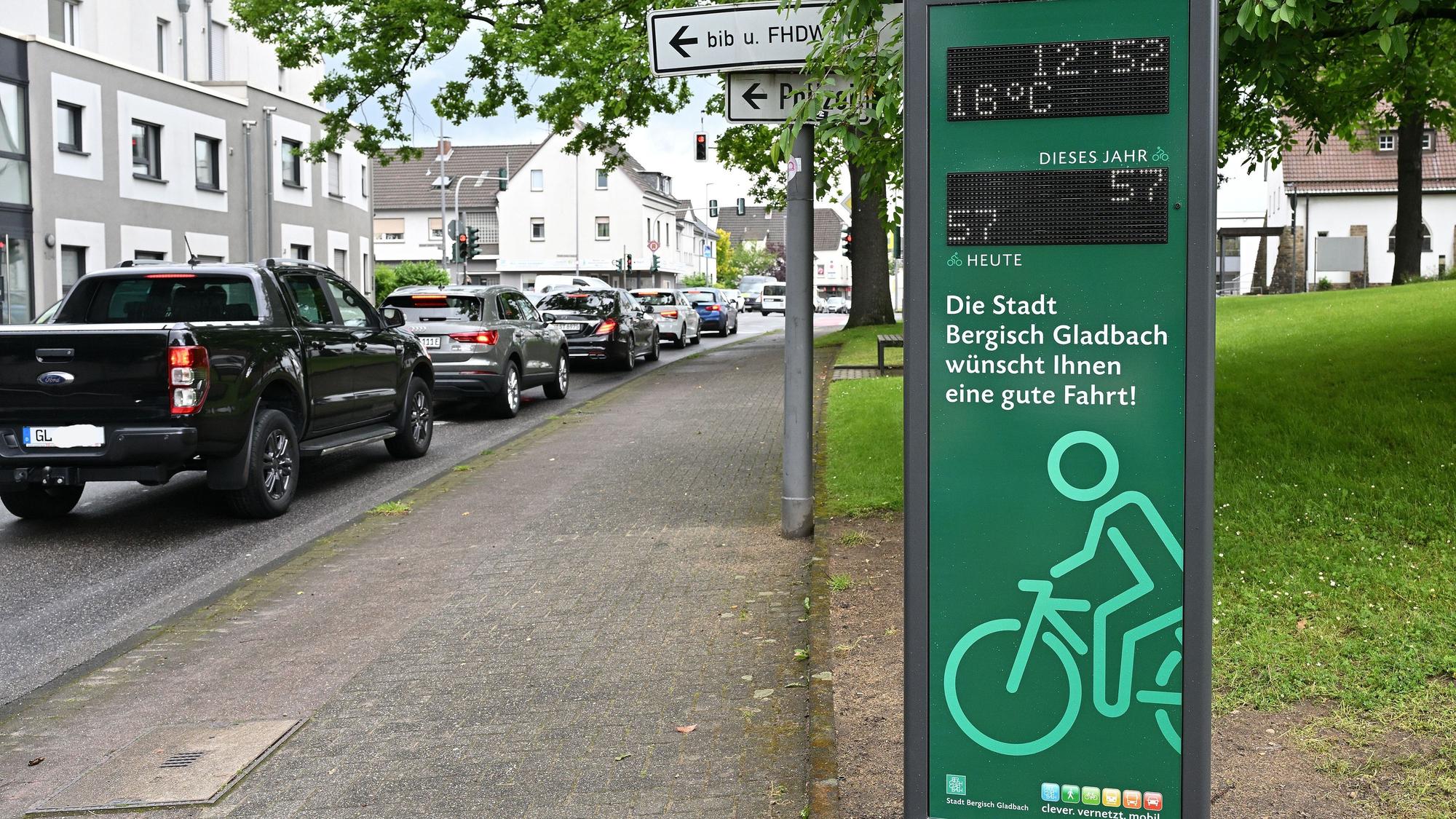 Autos in einer Schlange, daneben eine digitale Infosäule für Radfahrer