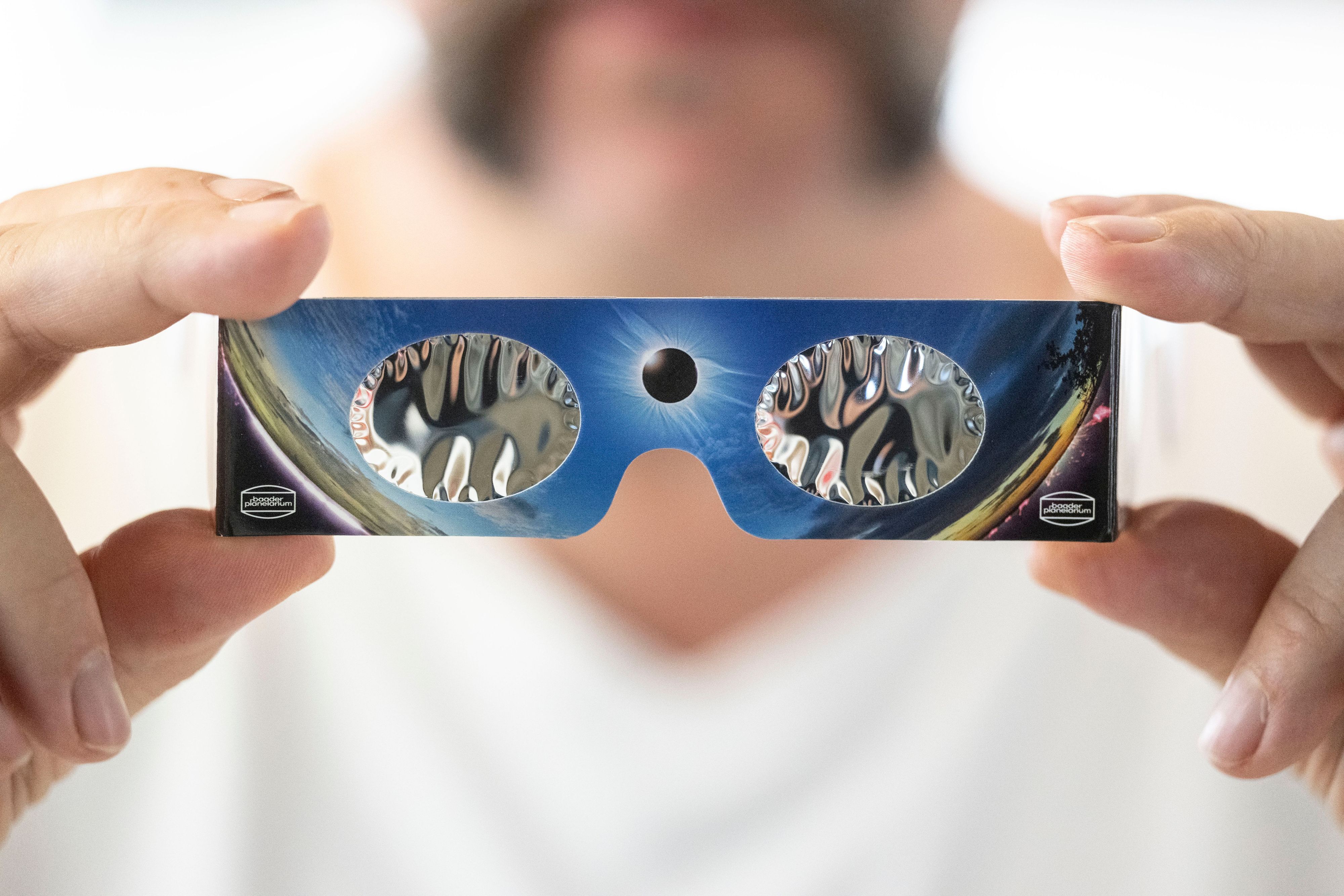Ein Angestellter hält in einem Fotofachhandelsgeschäft eine Sonnenfinsternis-Brille in der Hand.