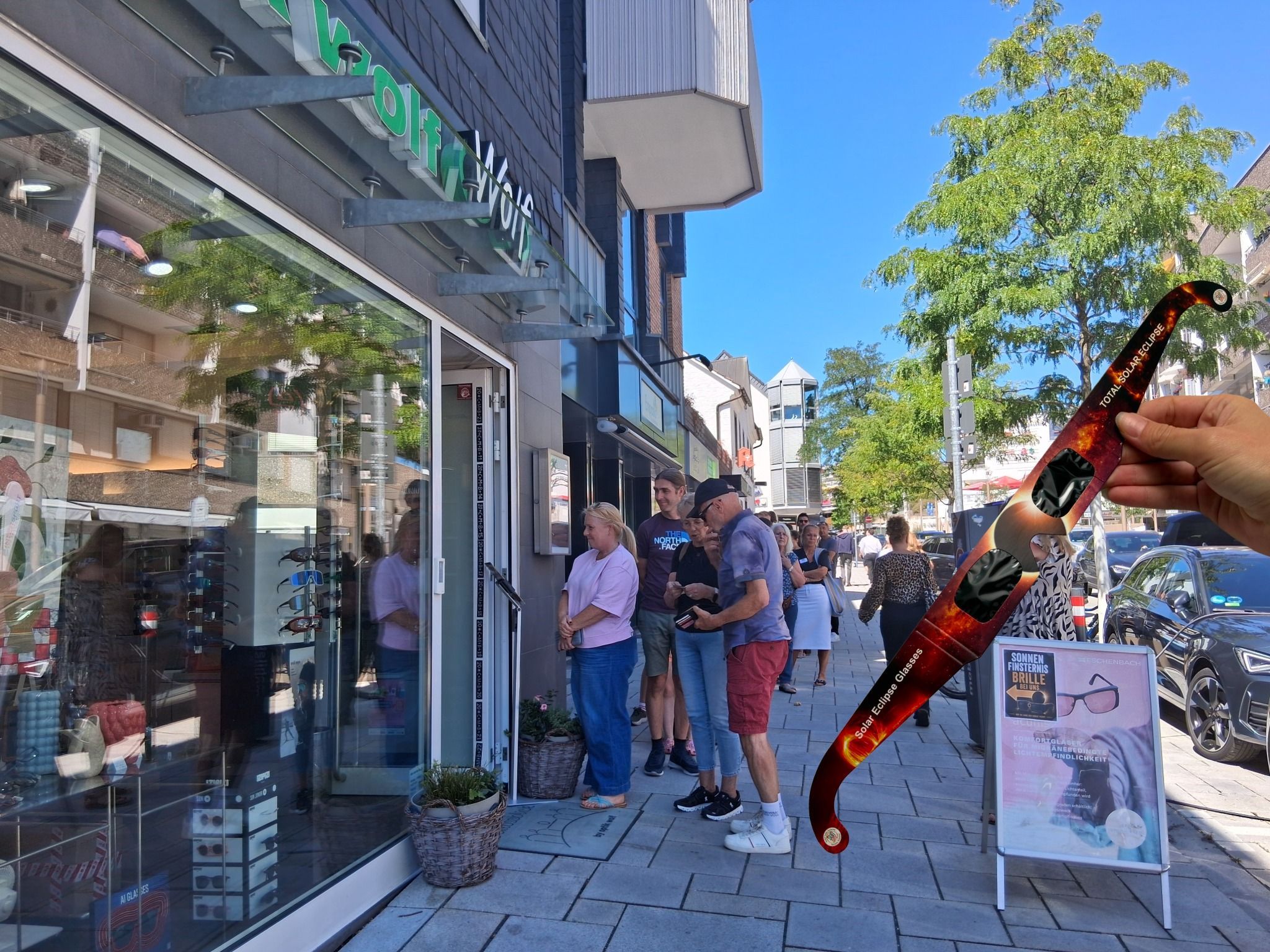 Menschenmasse vor dem Geschäft Optik Wolf. Rechts eine Sonnenfinsternisbrille. (Montage)