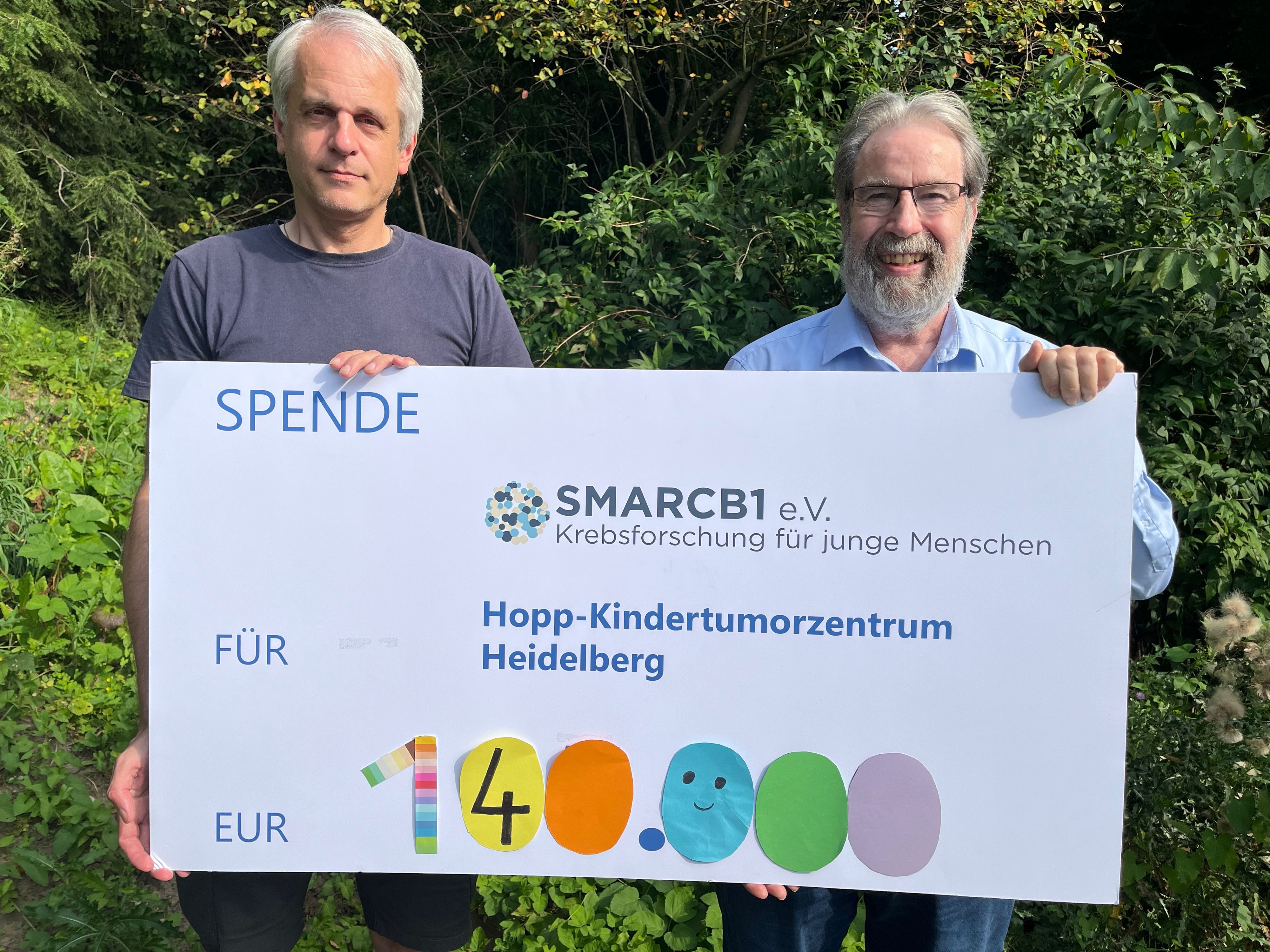 Zwei Männer halten einen Spendenscheck in der Hand.