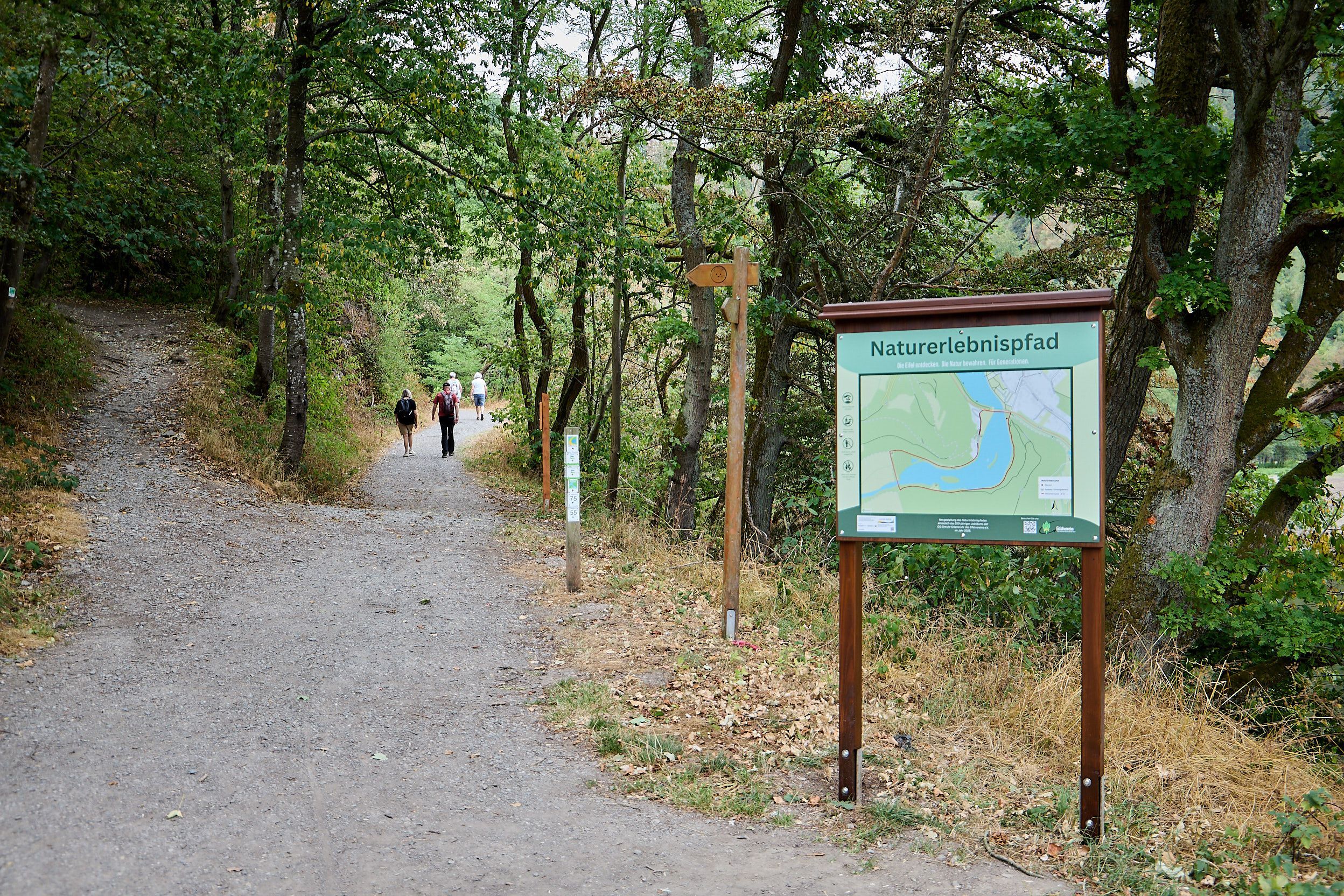 Eine Hinweistafel steht an einem Wanderweg.