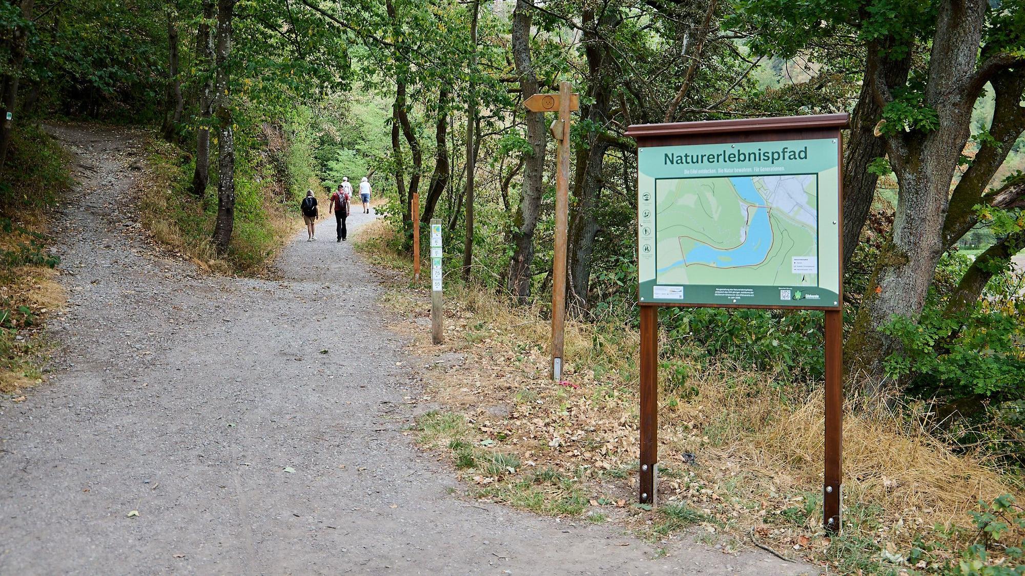 Eine Hinweistafel steht an einem Wanderweg.