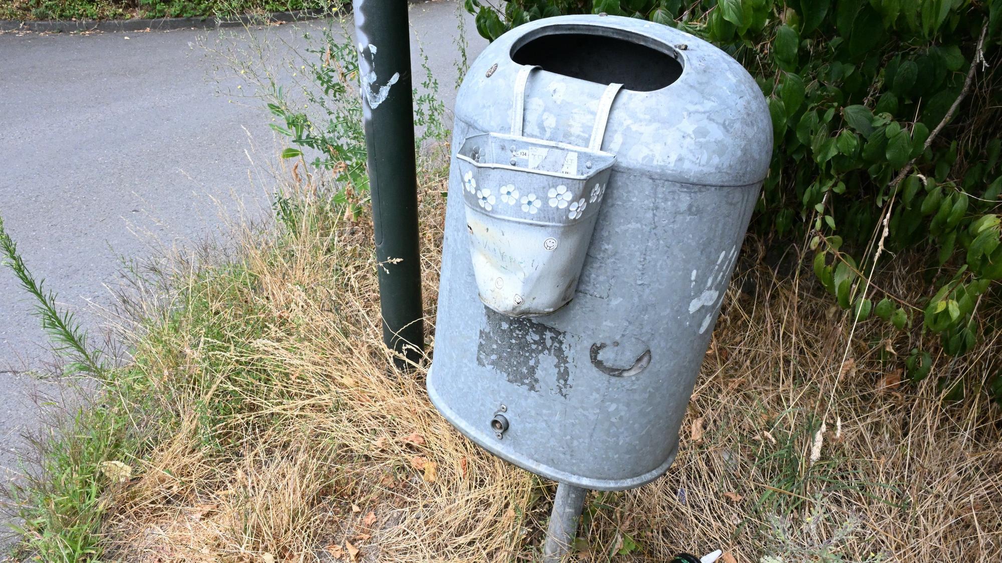 Zu sehen ist ein Mülleimer mit einem kleinen Blecheimer daran, in dem Kippenstummel entsorgt werden können.