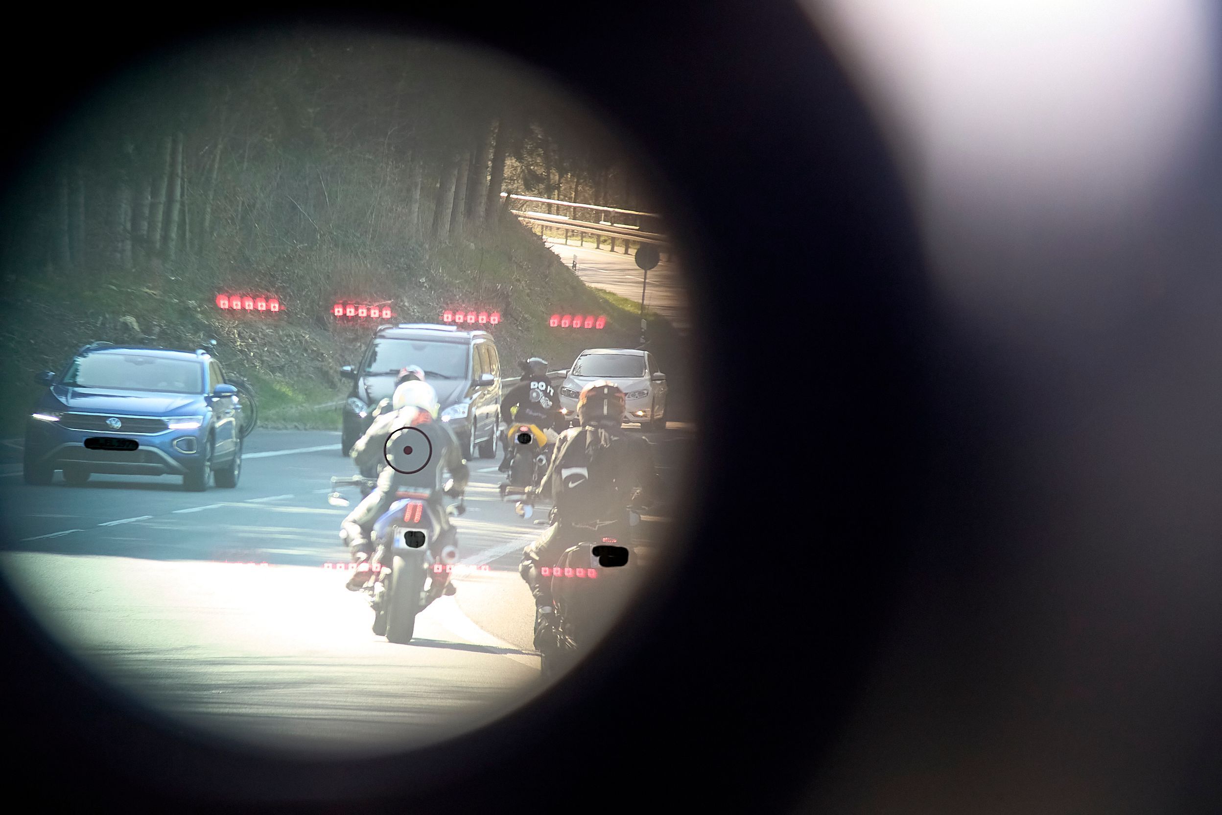 Das Symbolfoto ist durch ein Lasermessgerät der Polizei aufgenommen und zeigt den Blick auf eine von Motorrädern und Autos befahrene Straße.