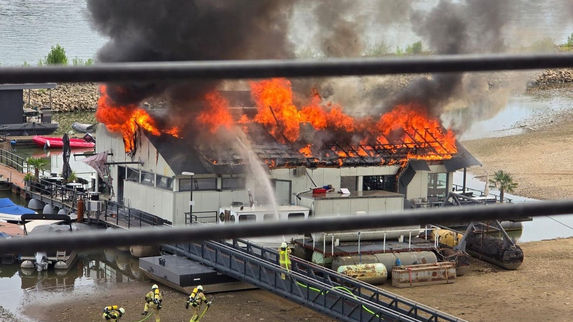 Das Dach des Sürther Bootshauses steht in Flammen.