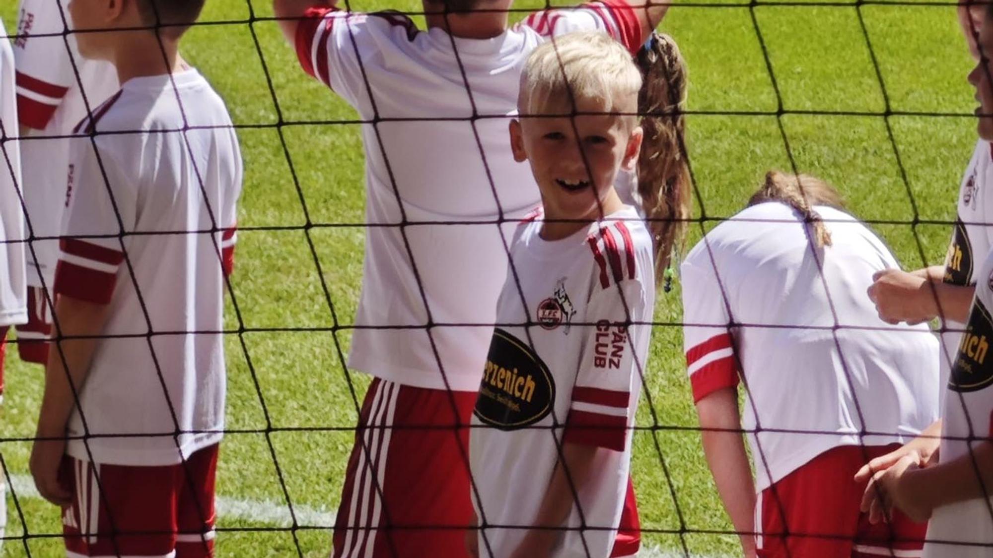 Elijah steht lächeln auf dem Platz neben den anderen Einlaufkindern.