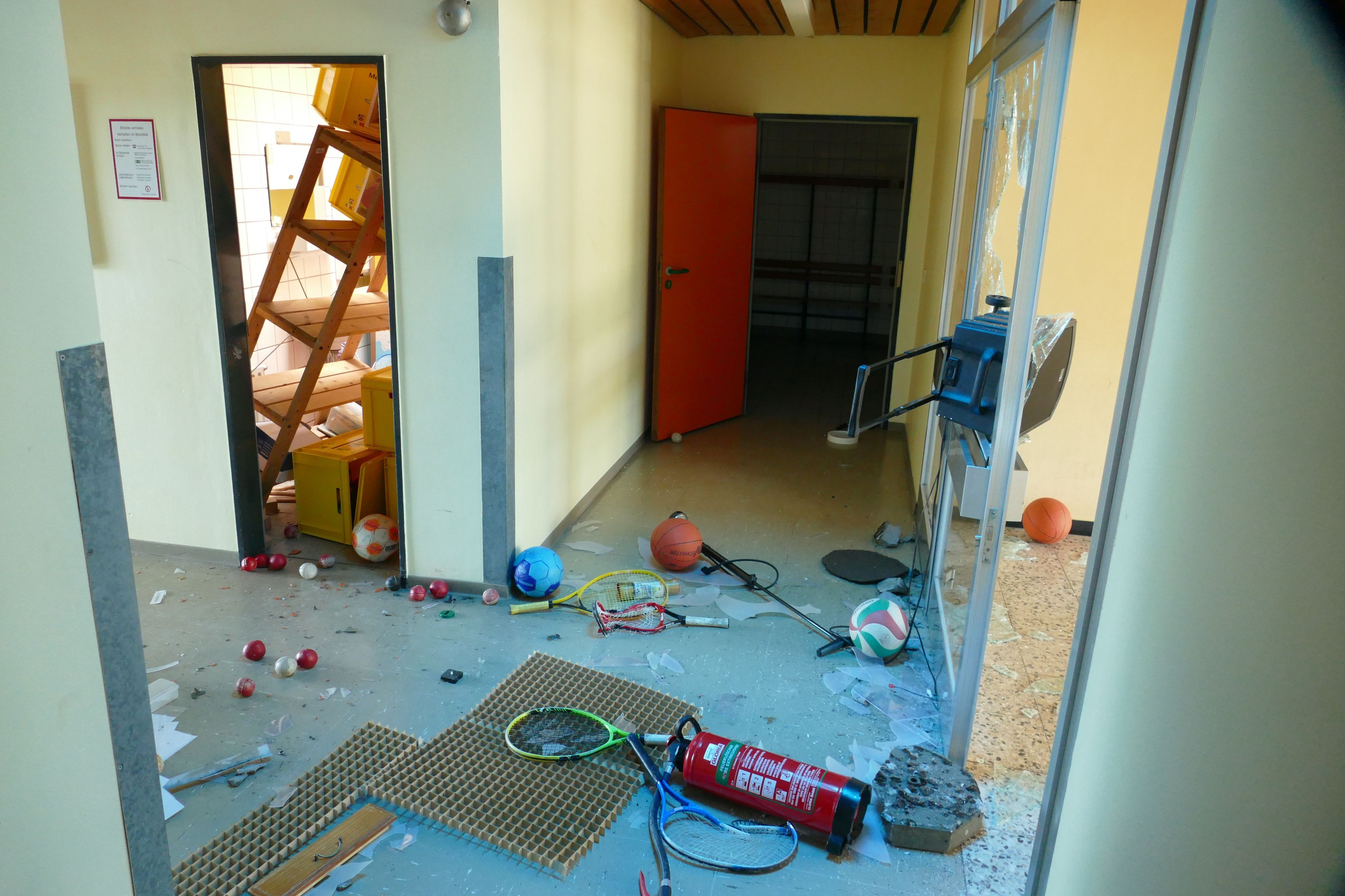 Spuren der Zerstörung in Räumen einer Schule. Am Boden liegt ein Feuerlöscher, in einem Nebenraum ist ein Regal umgekippt.