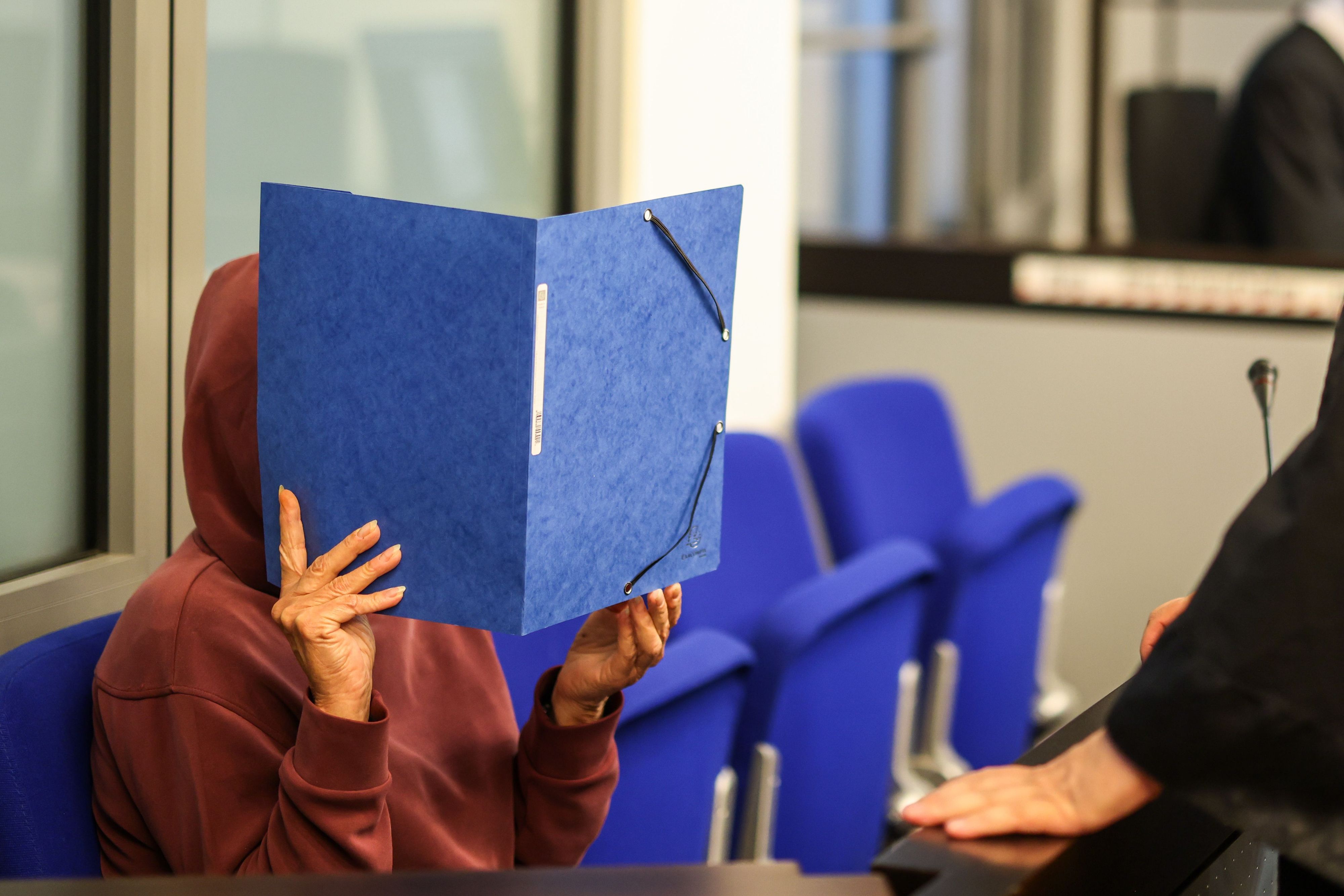 Beim Prozessbeginn vor dem Landgericht sitzt eine der beiden Angeklagten im Saal, ihr Gesicht verdeckt sie mit einem Aktendeckel.